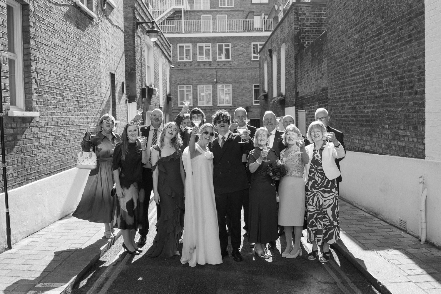 Wedding group portrait with guests lined up against urban architecture.