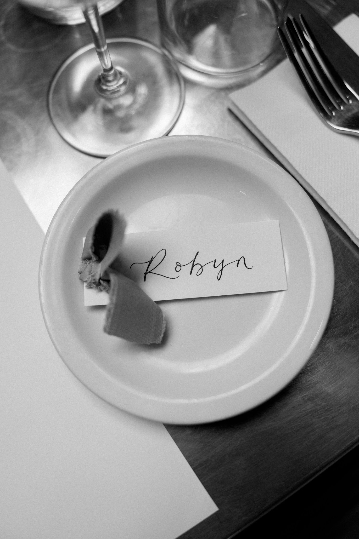 Black and white photo of elegant place settings with handwritten name cards.