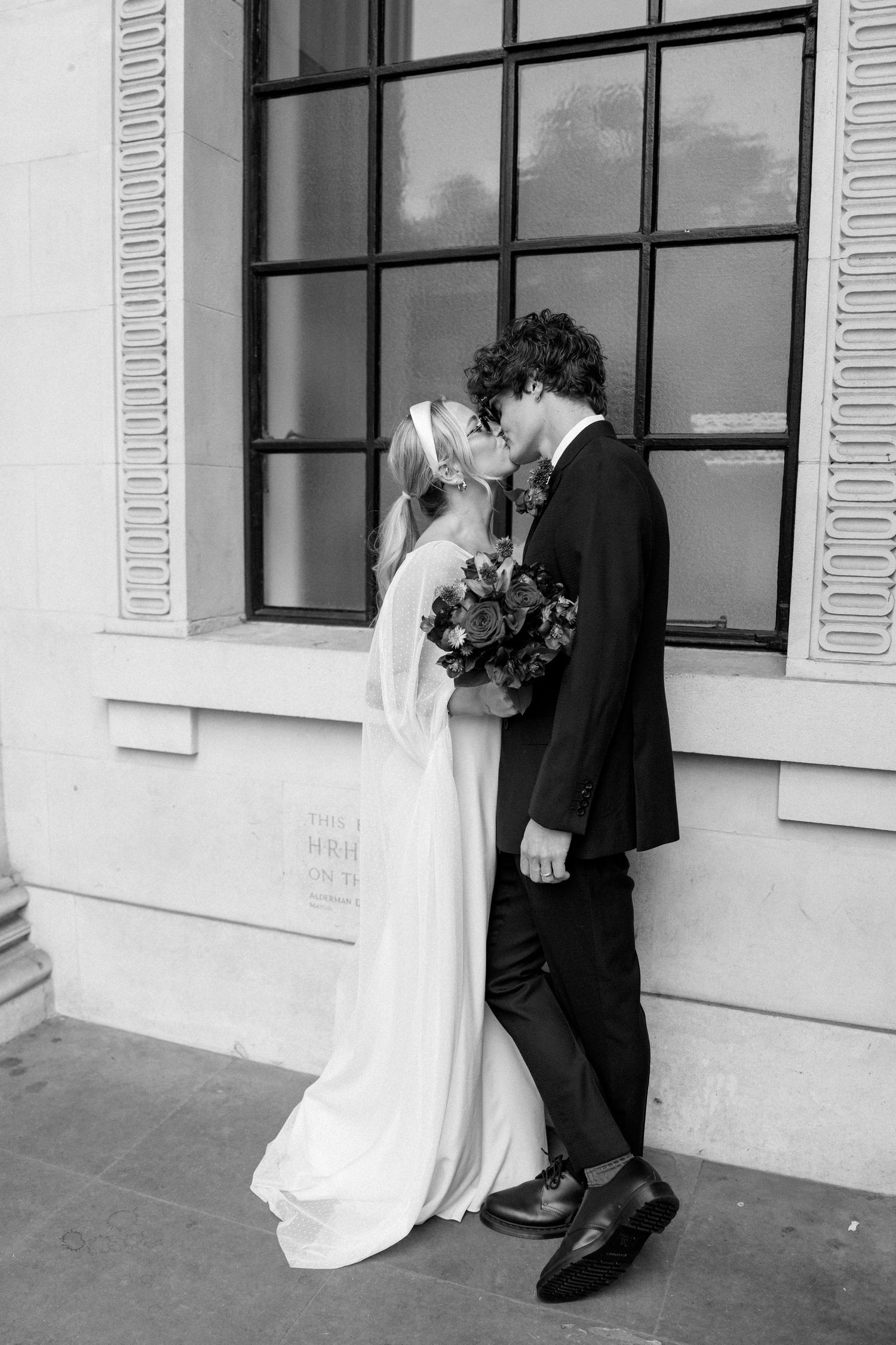 Artistic wedding photo sequence showing romantic moments between newlyweds against a white building facade.