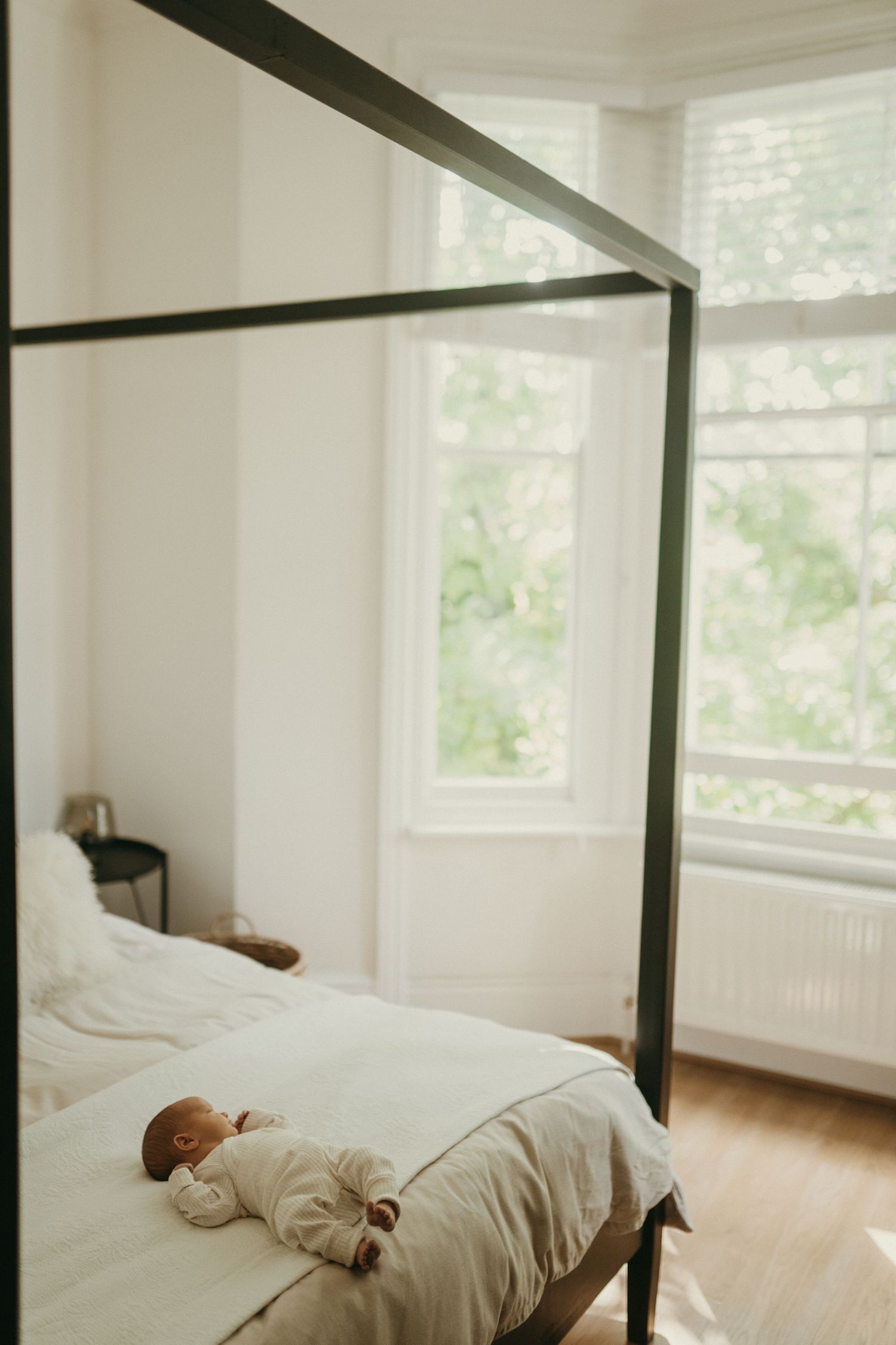 A minimalist bedroom with white bedding and natural light streaming through windows.