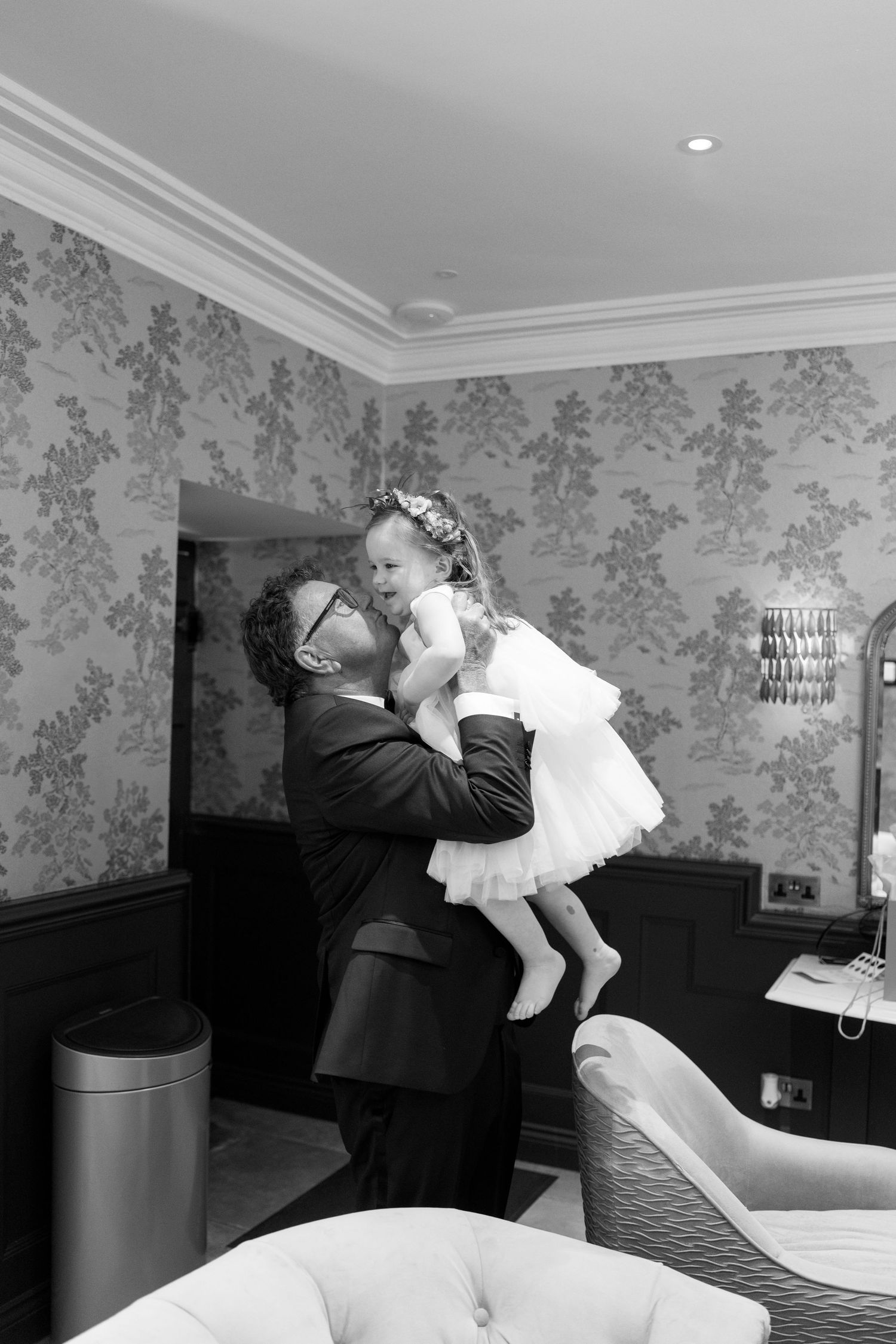 Sweet moment captured during wedding preparations in an elegantly wallpapered room.