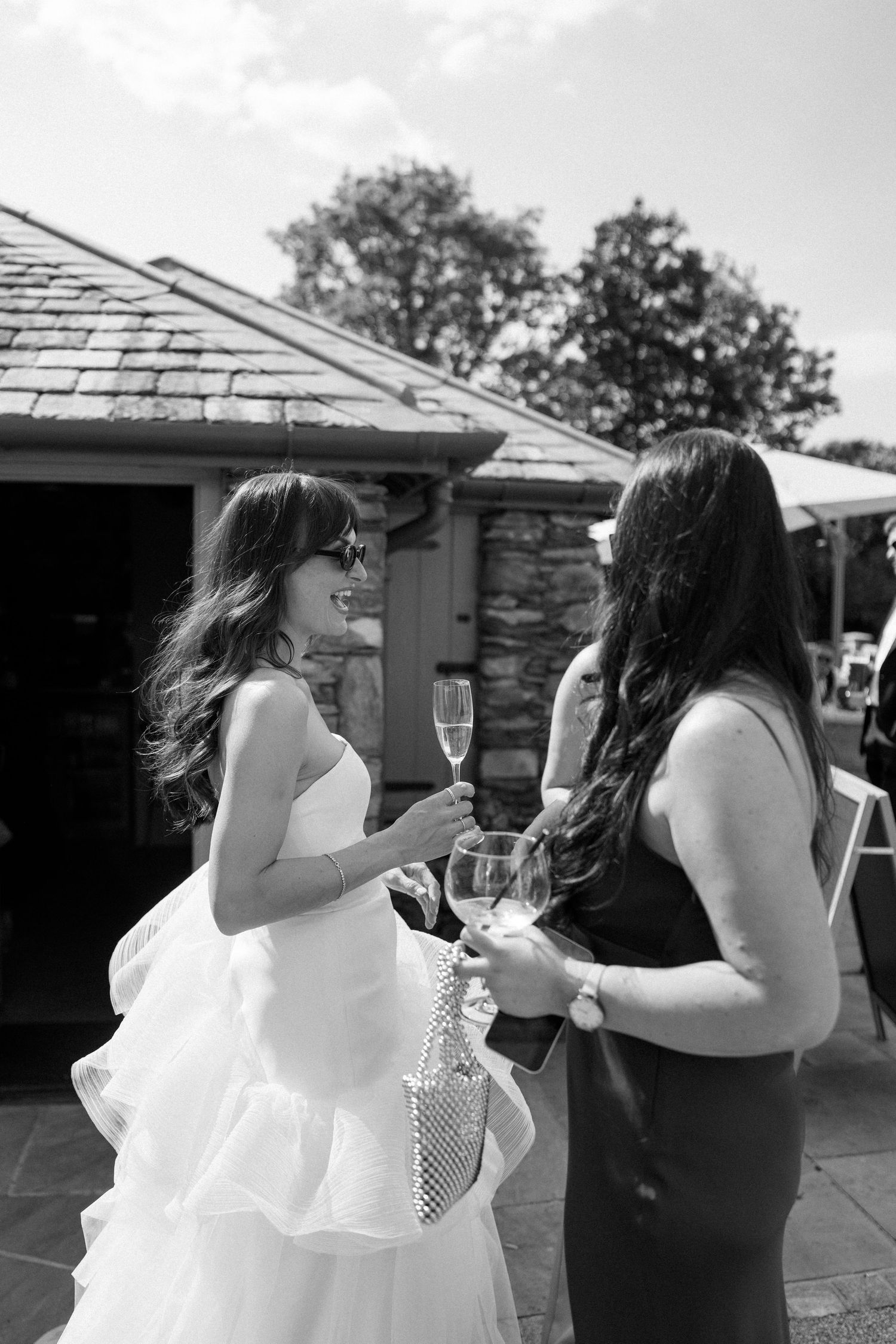 Wedding party members in formal attire toasting with champagne glasses outdoors.
