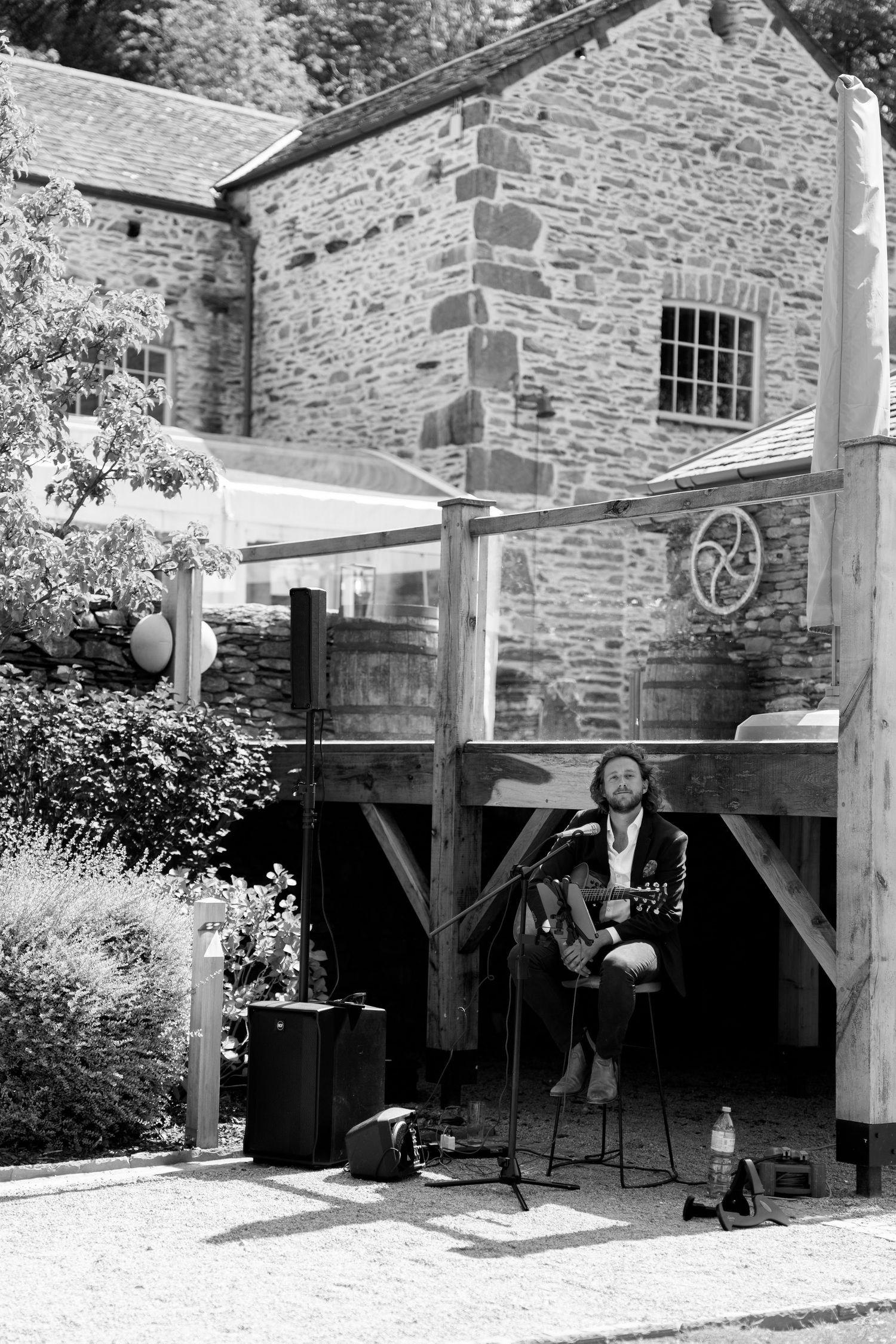 A musician performs under a stone archway at an outdoor venue.