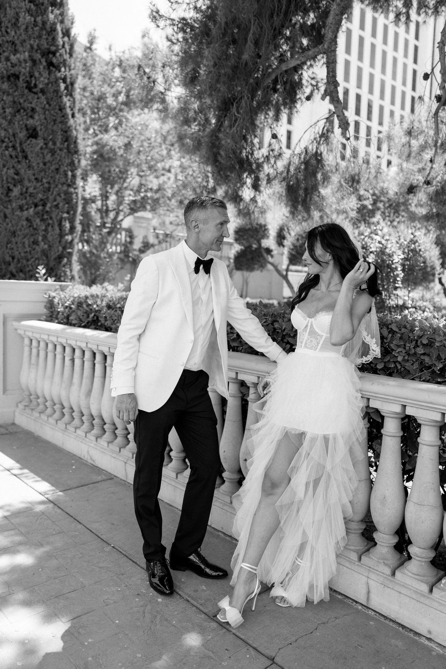 A black and white wedding photo on an elegant balcony with stone railings.