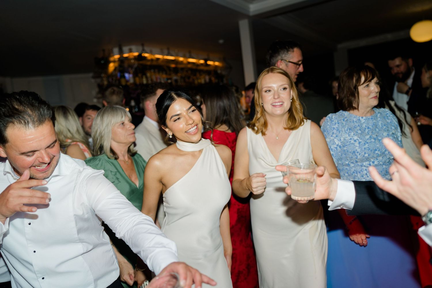 Guests in elegant attire dance and celebrate at a lively wedding reception party.