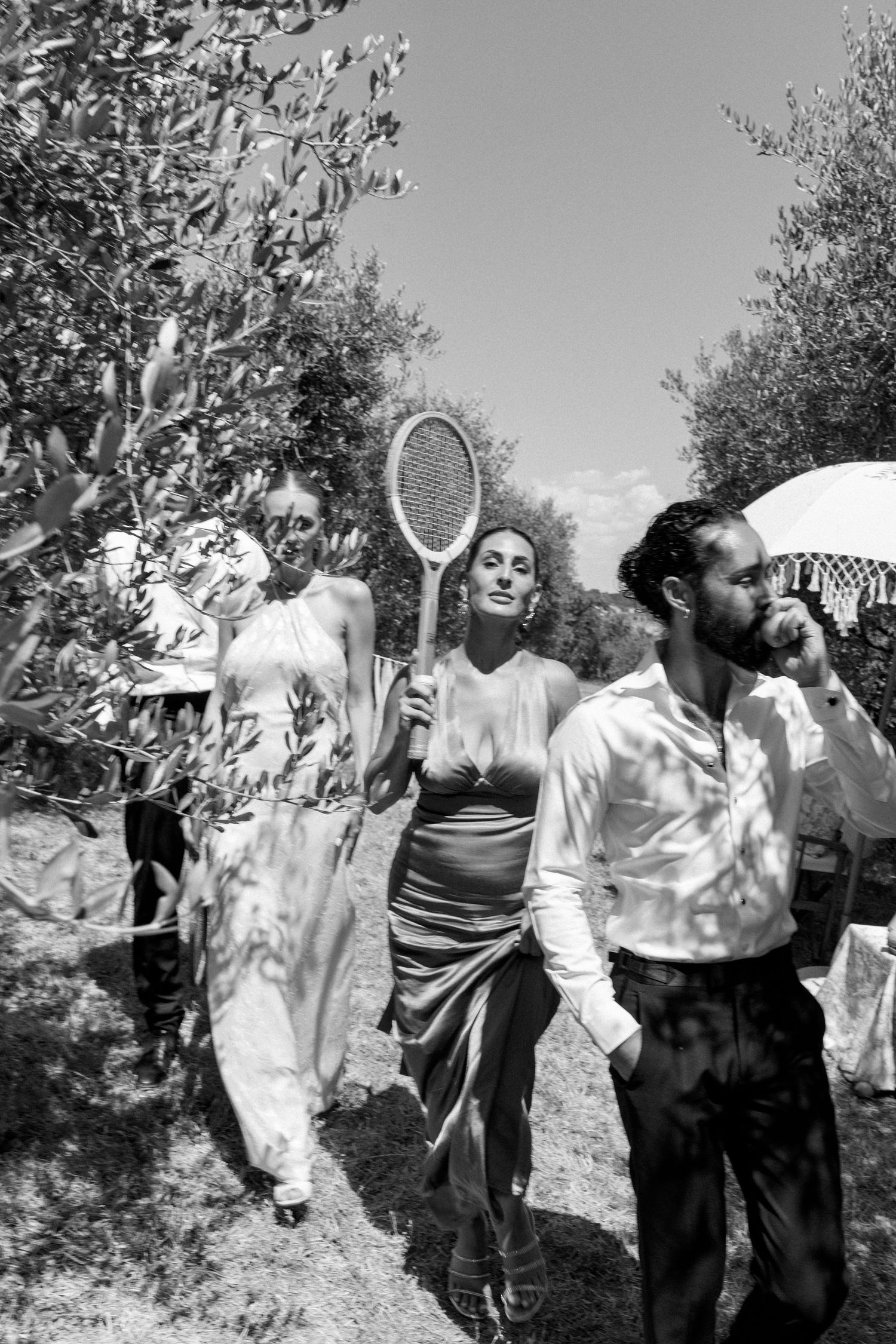 Vintage black and white photo of people playing outdoor games in an olive grove.