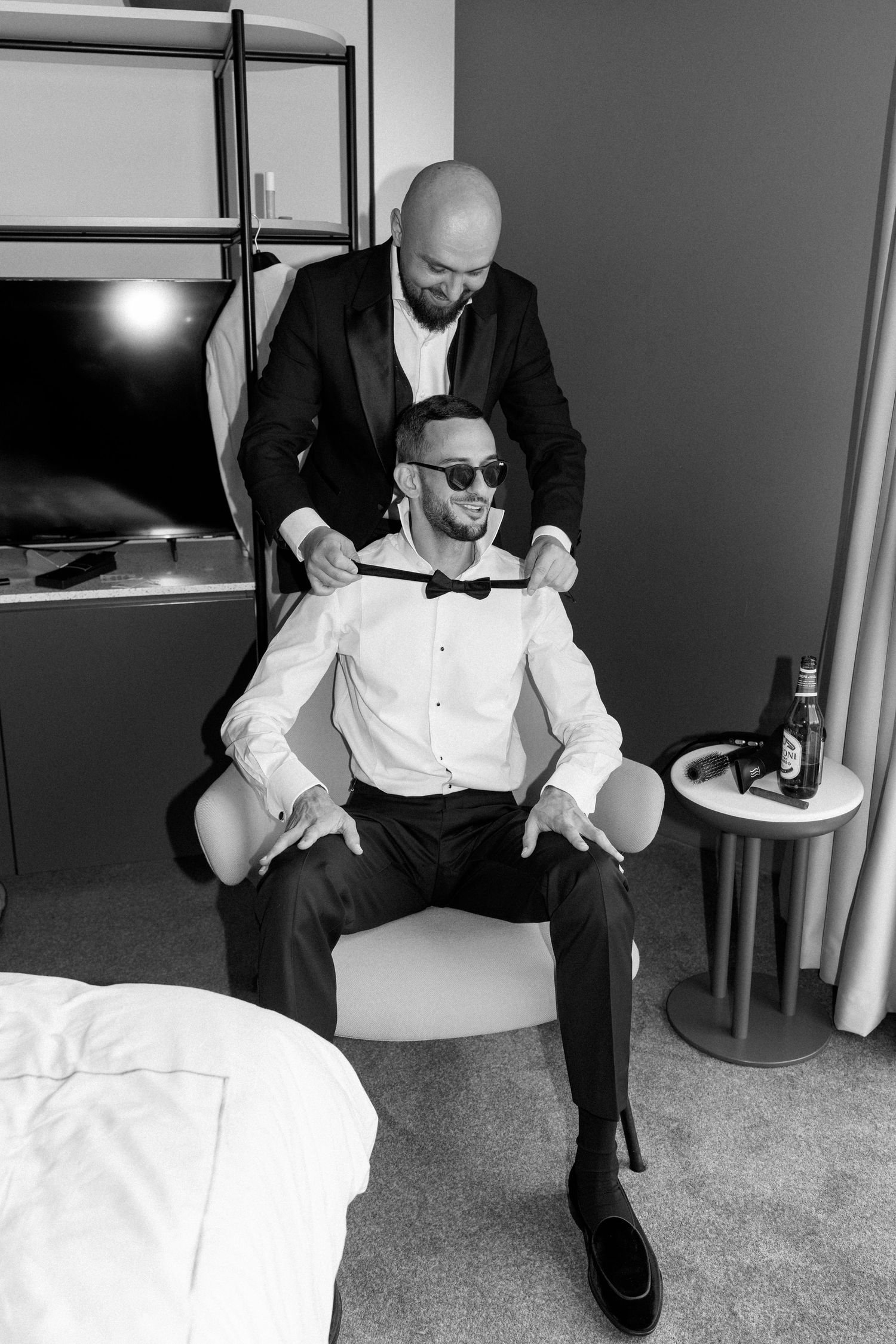Black and white photo series showing someone getting dressed in formal attire and putting on a white shirt.