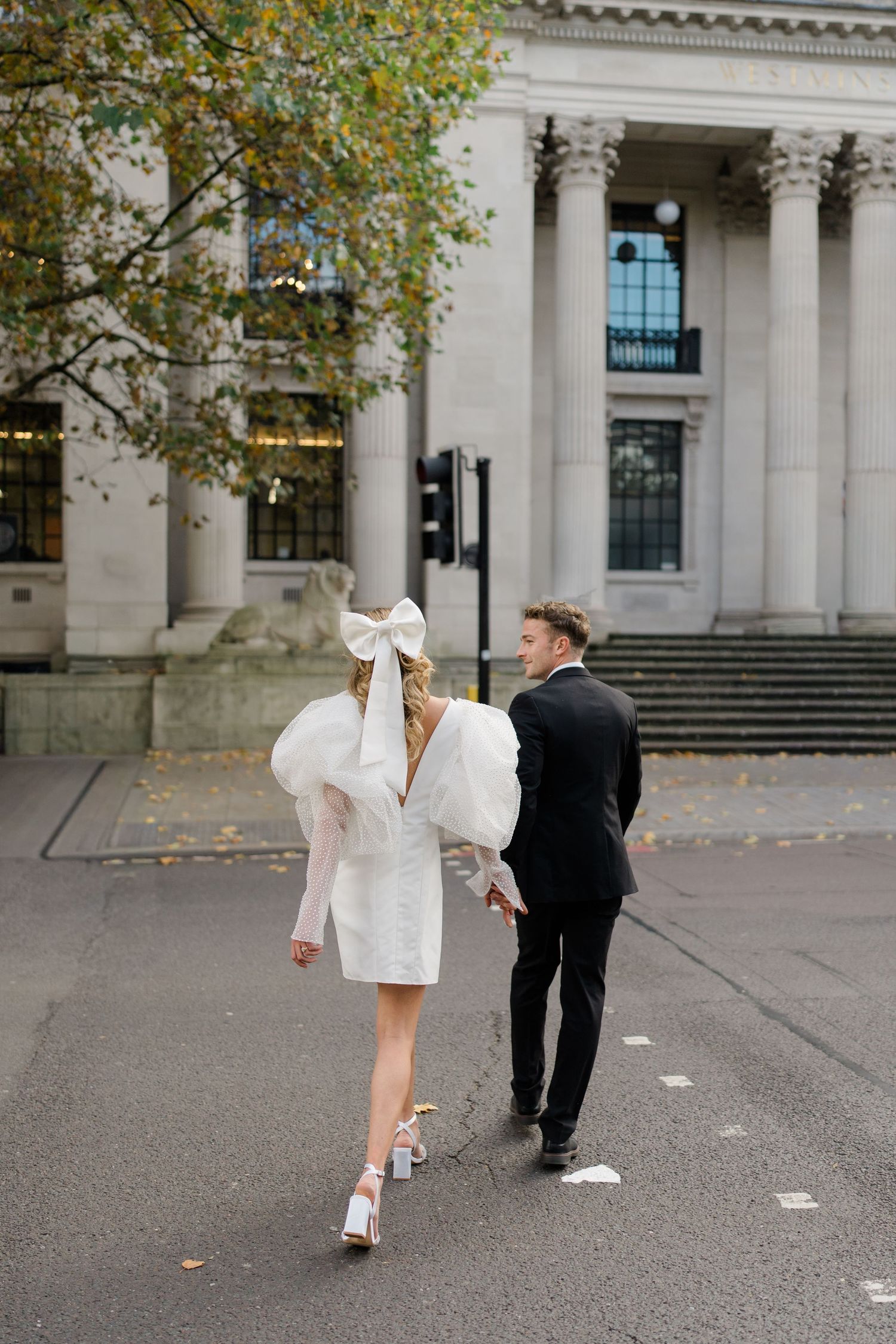 A couple dancing playfully in front of a grand building with columns.