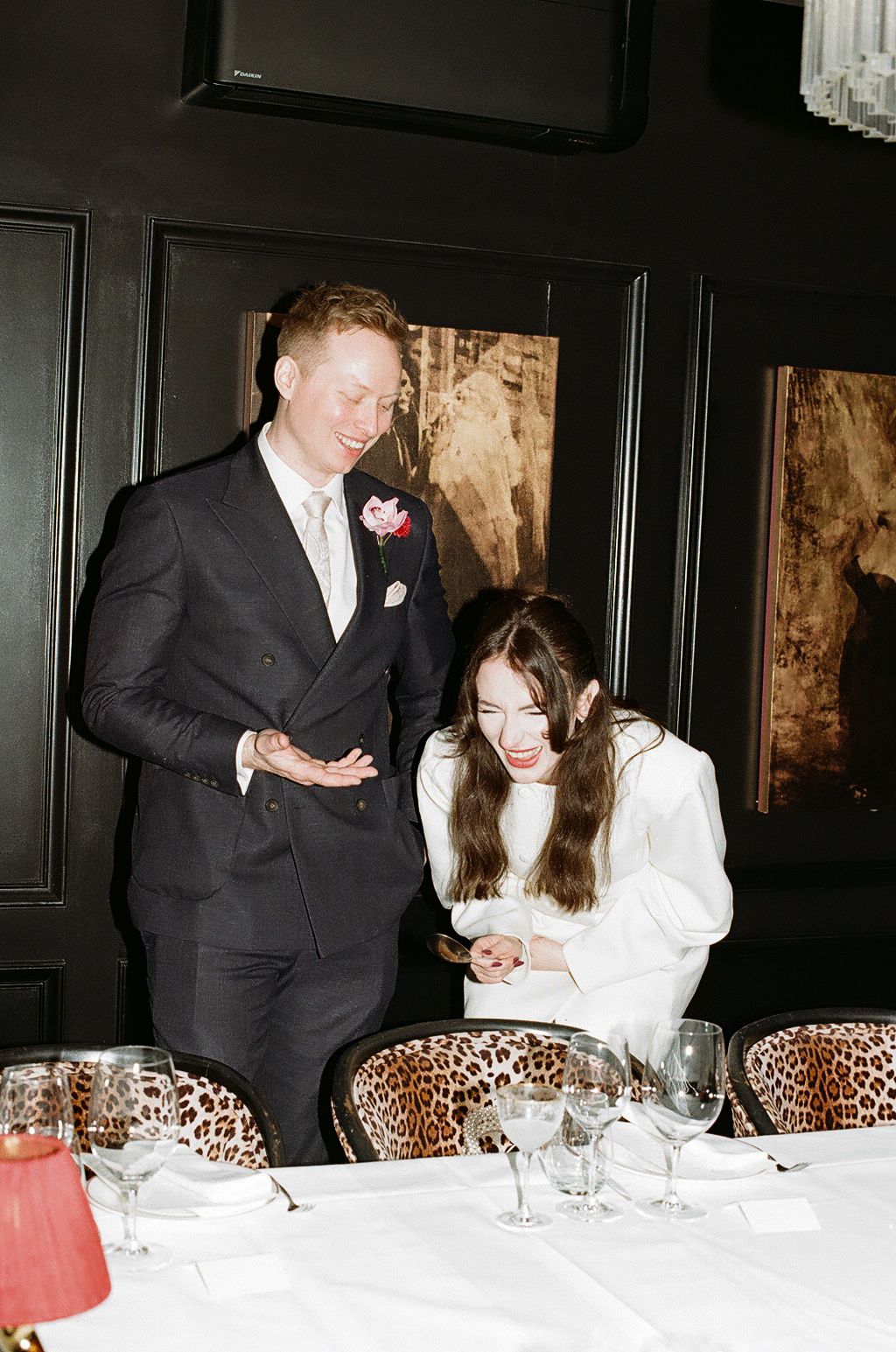 Diners seated at an elegant restaurant table with leopard print chairs and dark wood paneling.