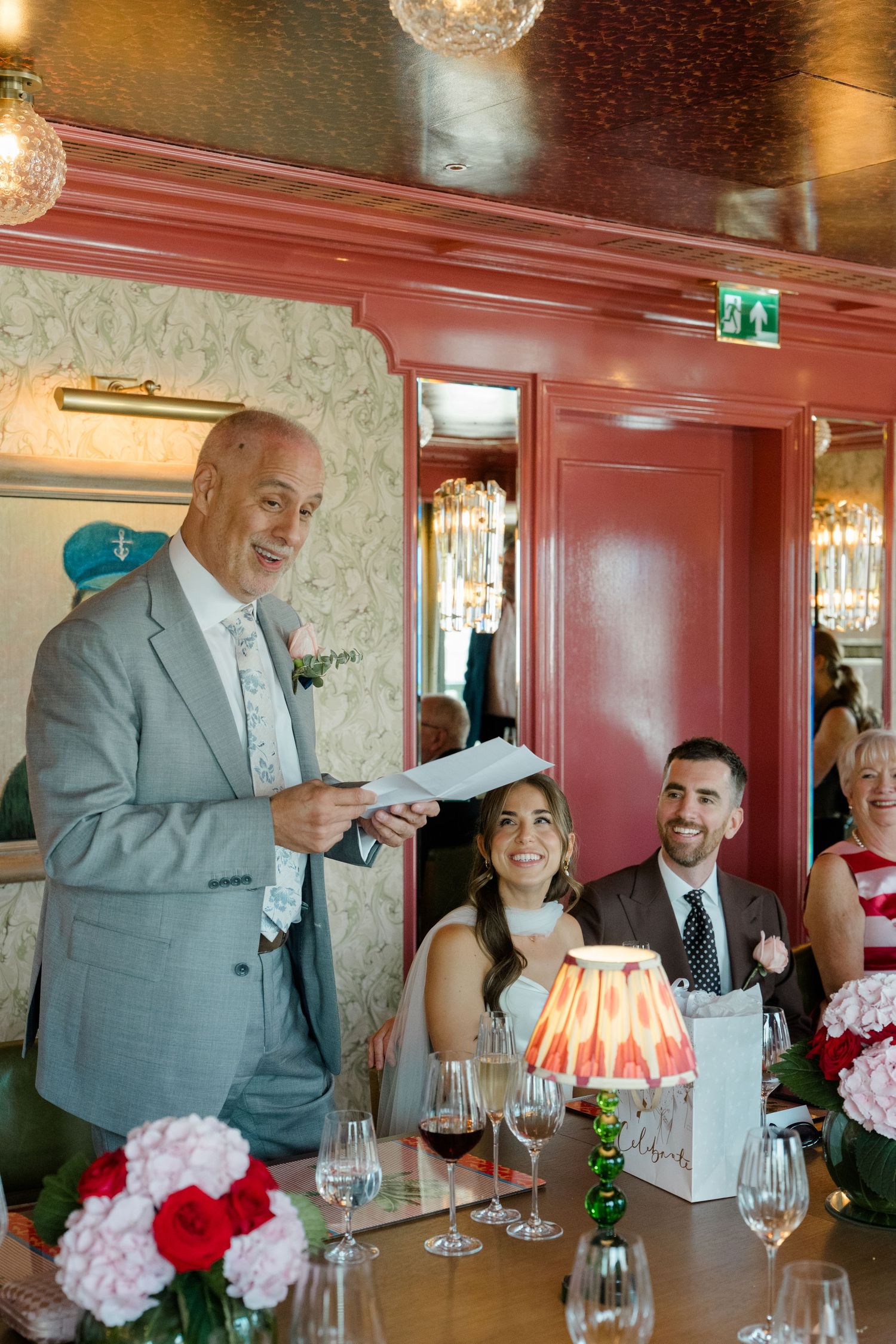 Father of the bride gives a heartfelt speech to smiling newlyweds at a wedding reception dinner.