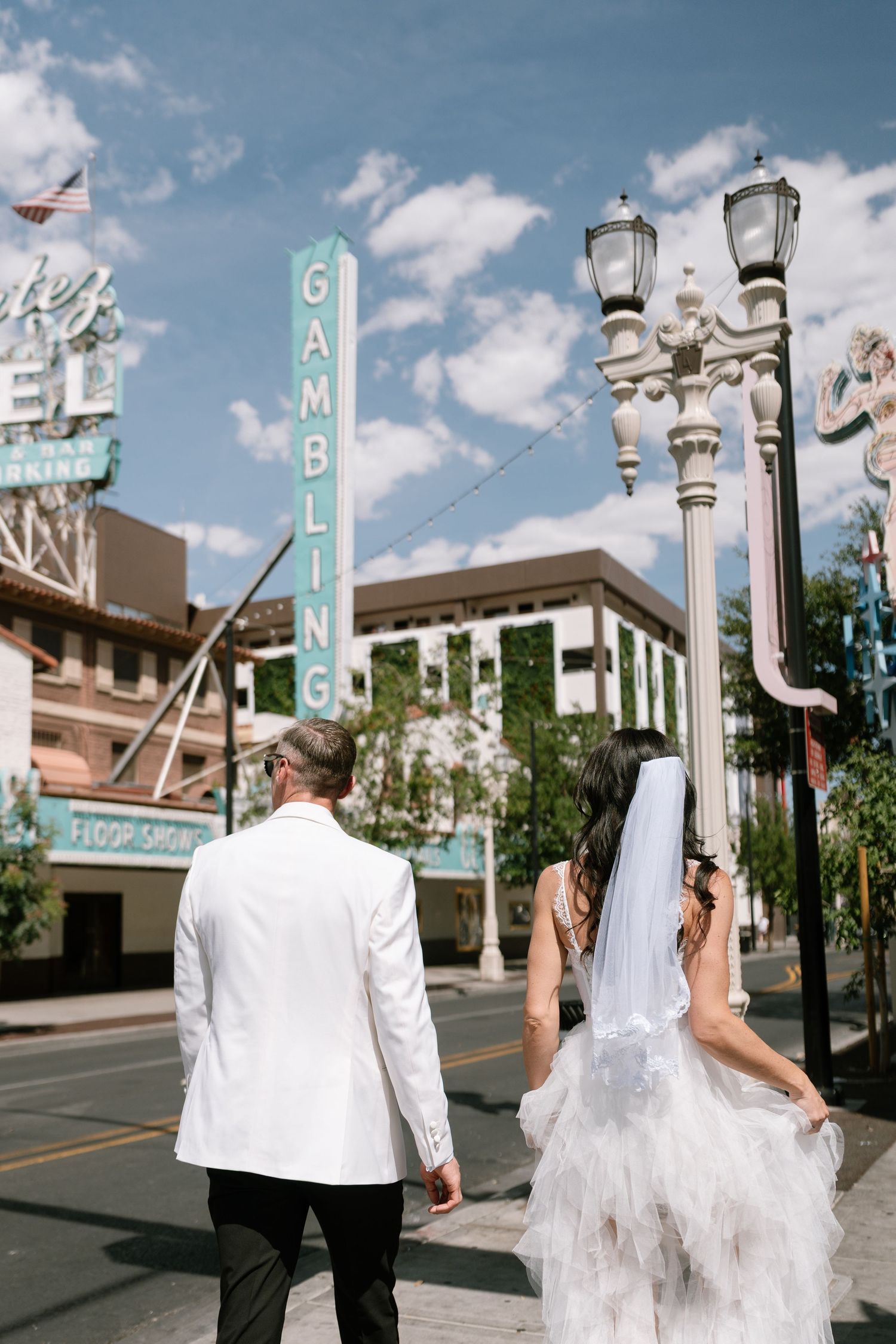 Wedding couple walking past Gambling sign and ornate street lamps in Las Vegas.