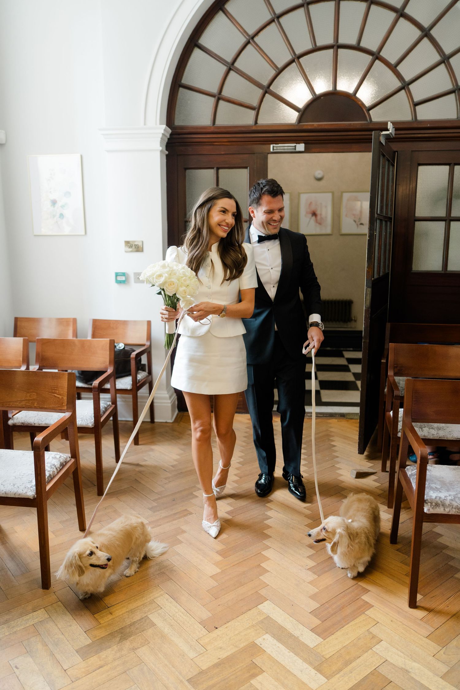 Bride and groom walking dogs down the aisle at a registry office.