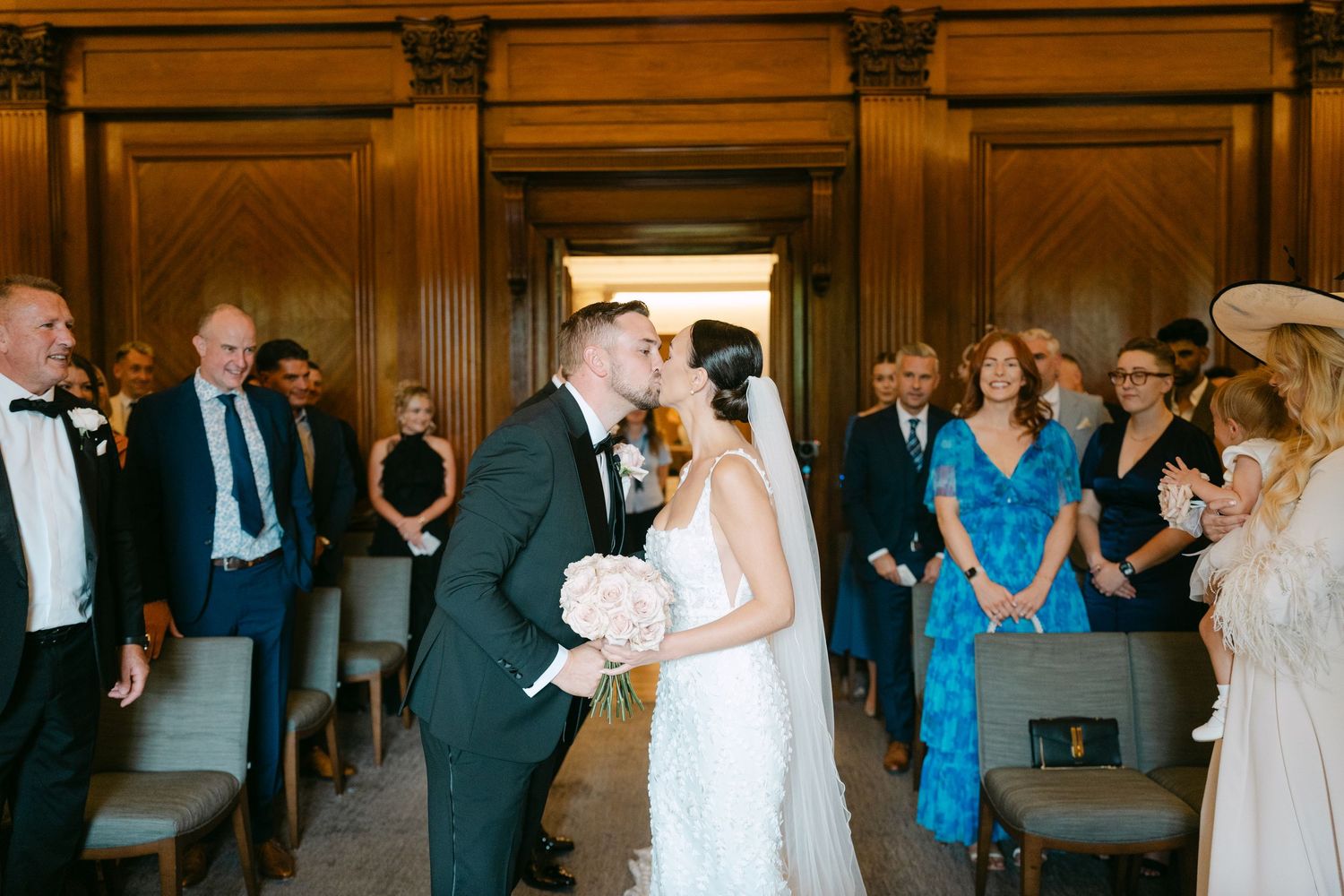 Wedding celebration in progress inside an ornate venue with wood-paneled walls.