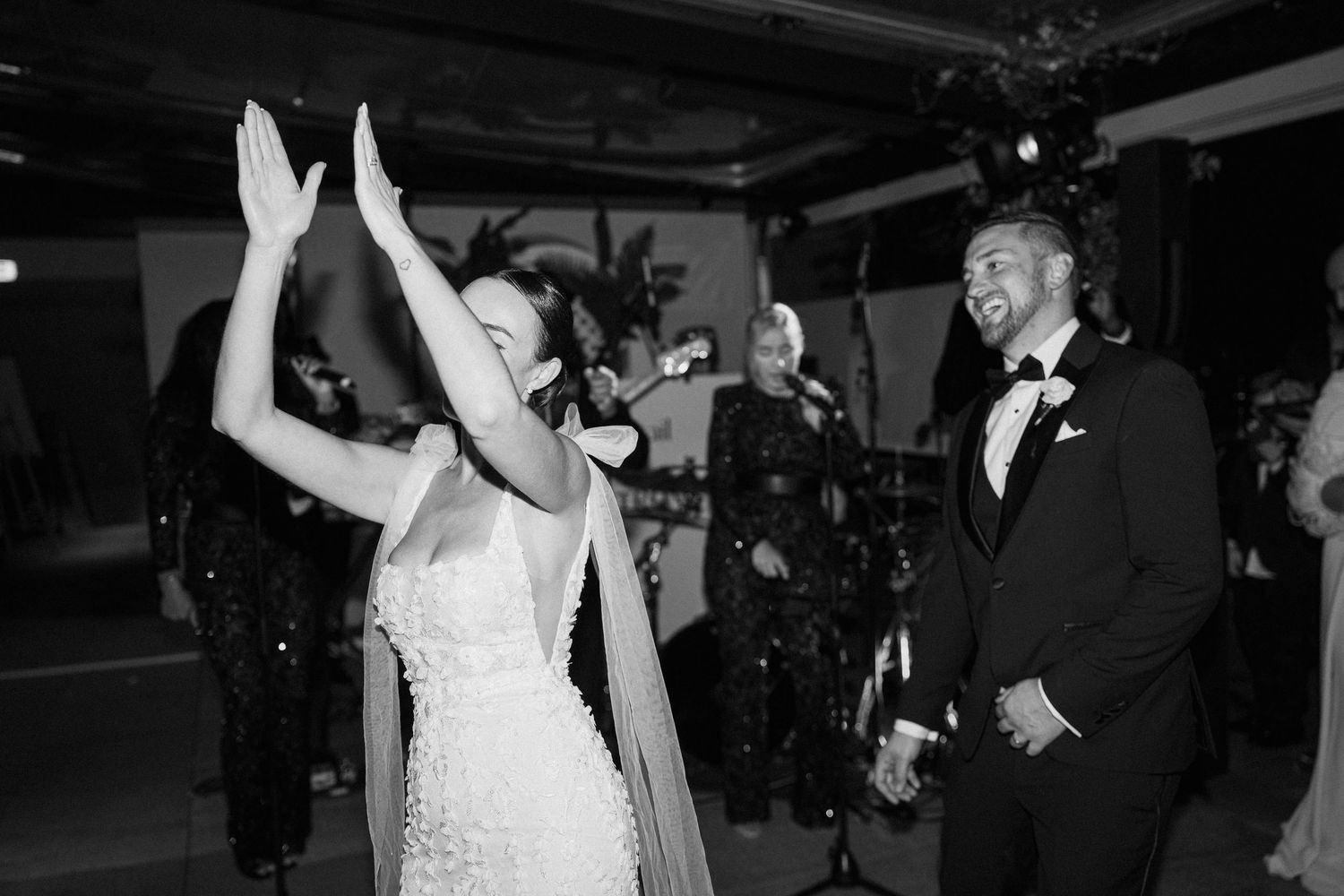 A couple dances together at their wedding reception while guests watch in the background.