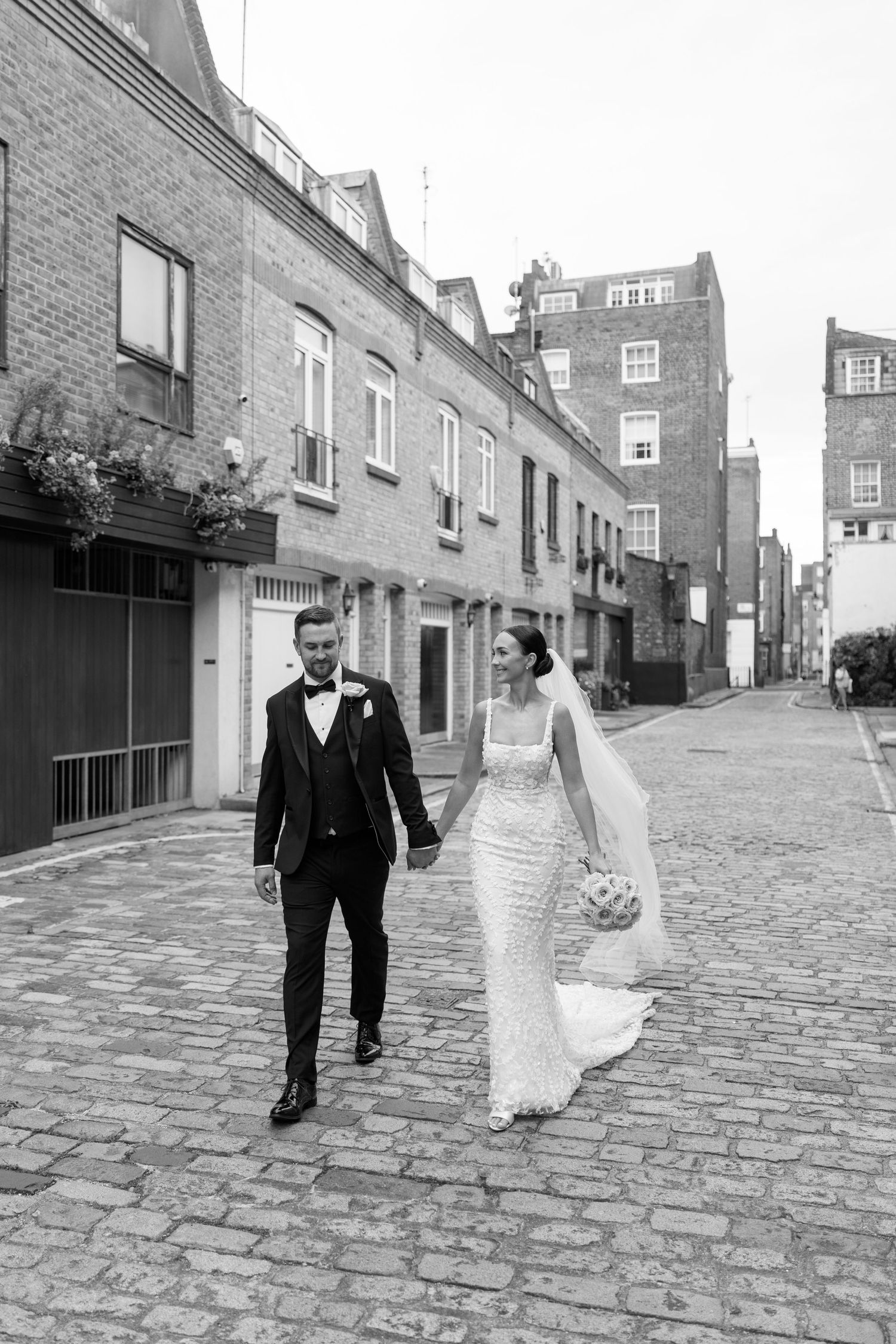 Black and white photos of a wedding couple strolling down a historic cobblestone street.