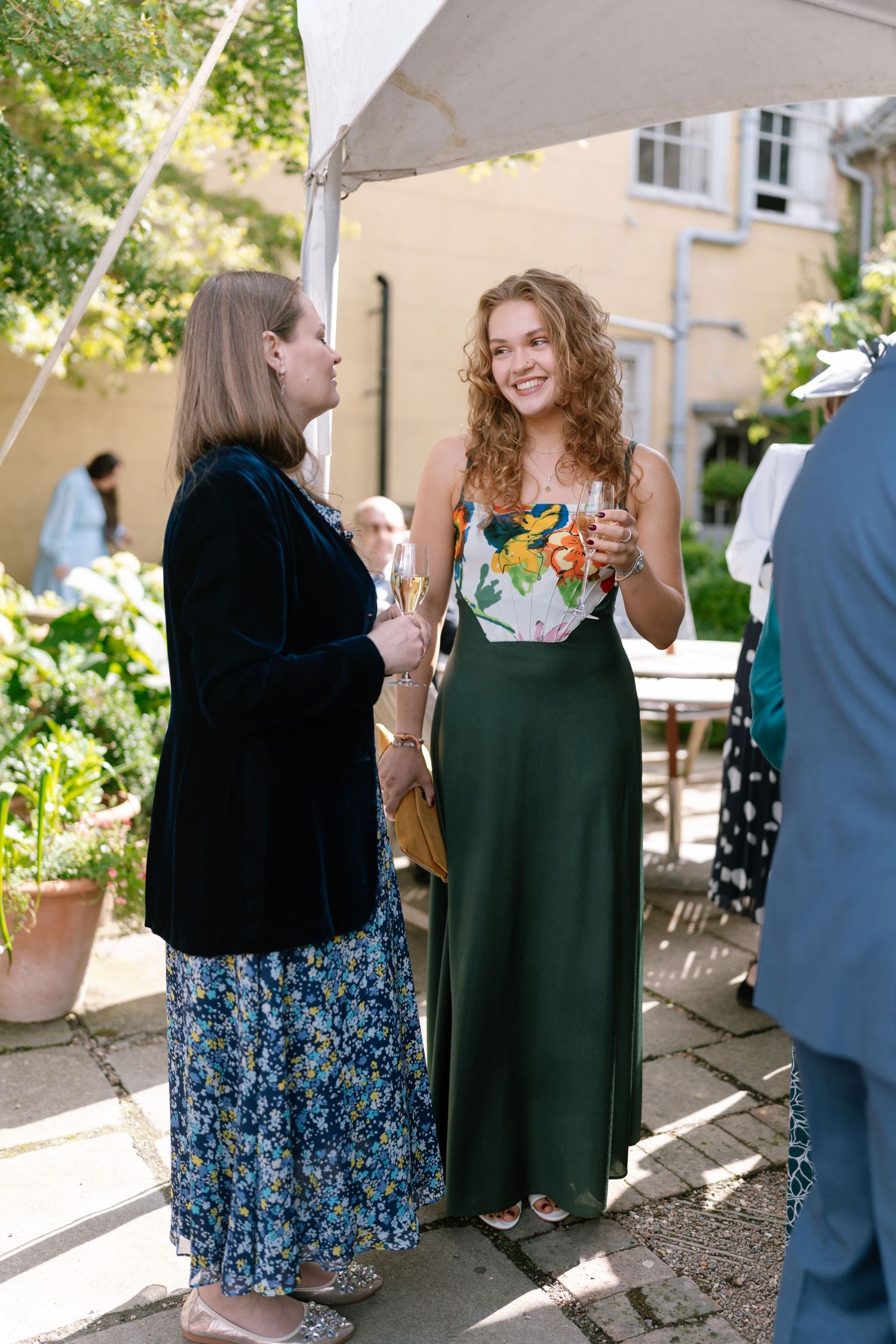 Wedding guests mingling at an outdoor reception under white tents.