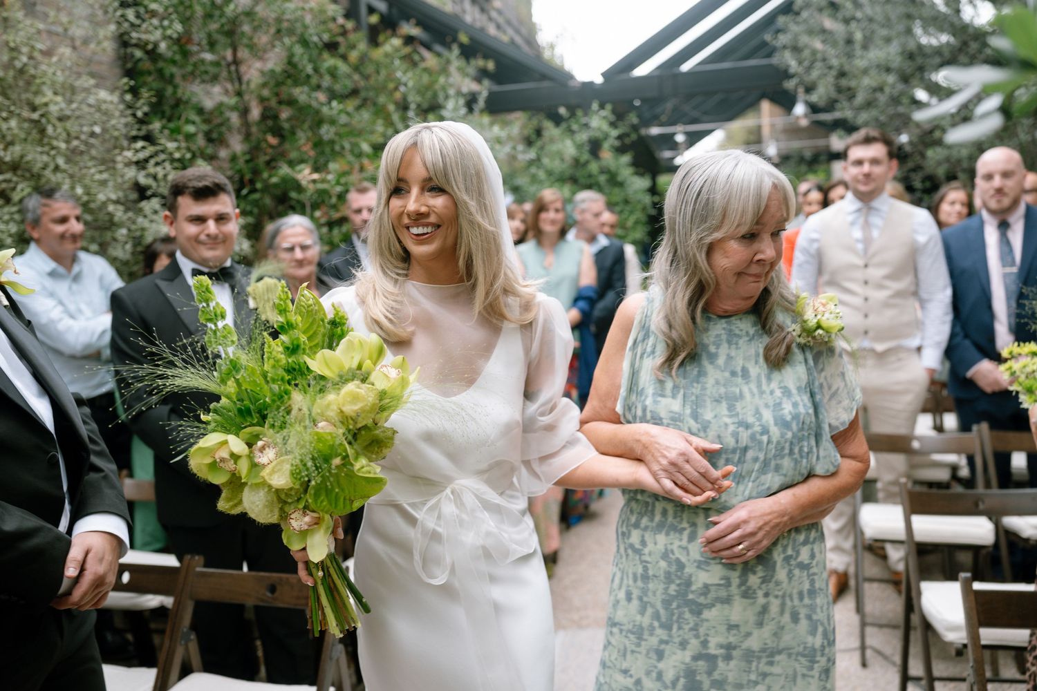 Wedding party and guests celebrating outdoors at a garden reception venue.
