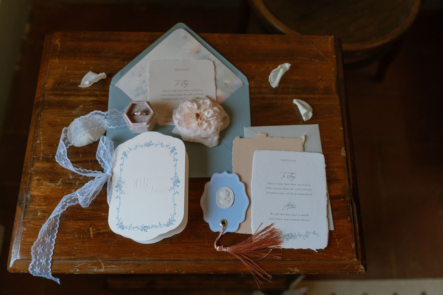 Wedding stationery and invitation suite featuring delicate blue and white designs laid out on a wooden surface.