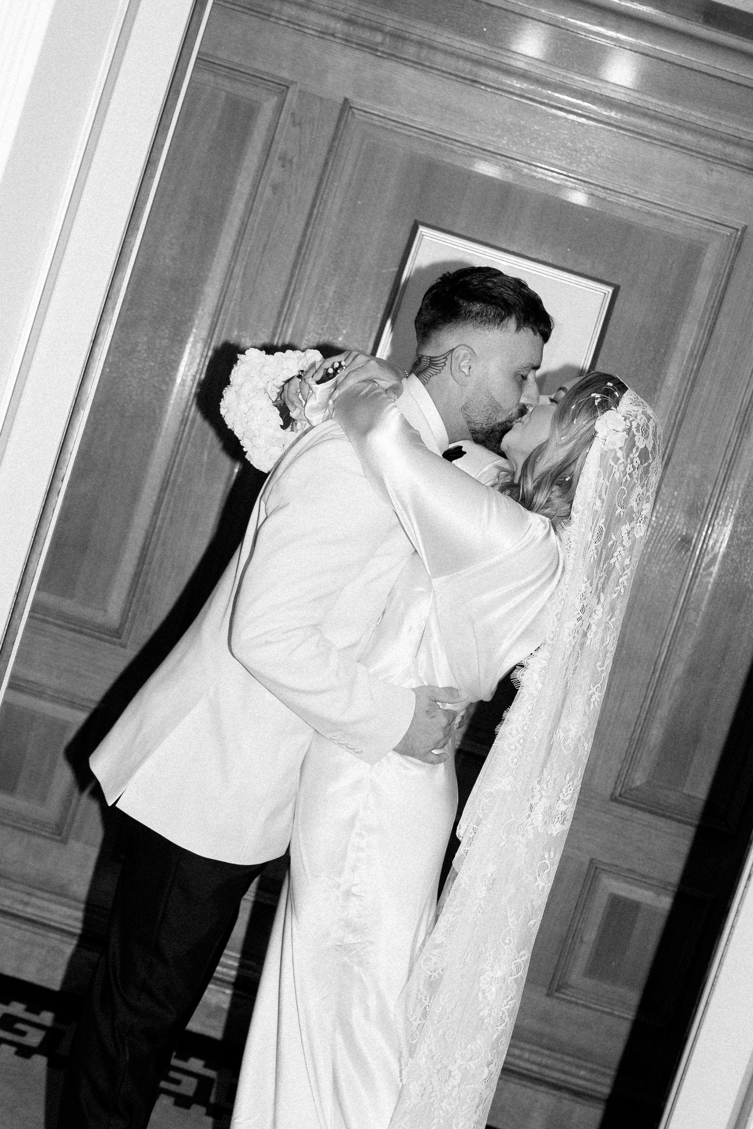 Black and white sequence showing couple in formal attire near wooden doors.