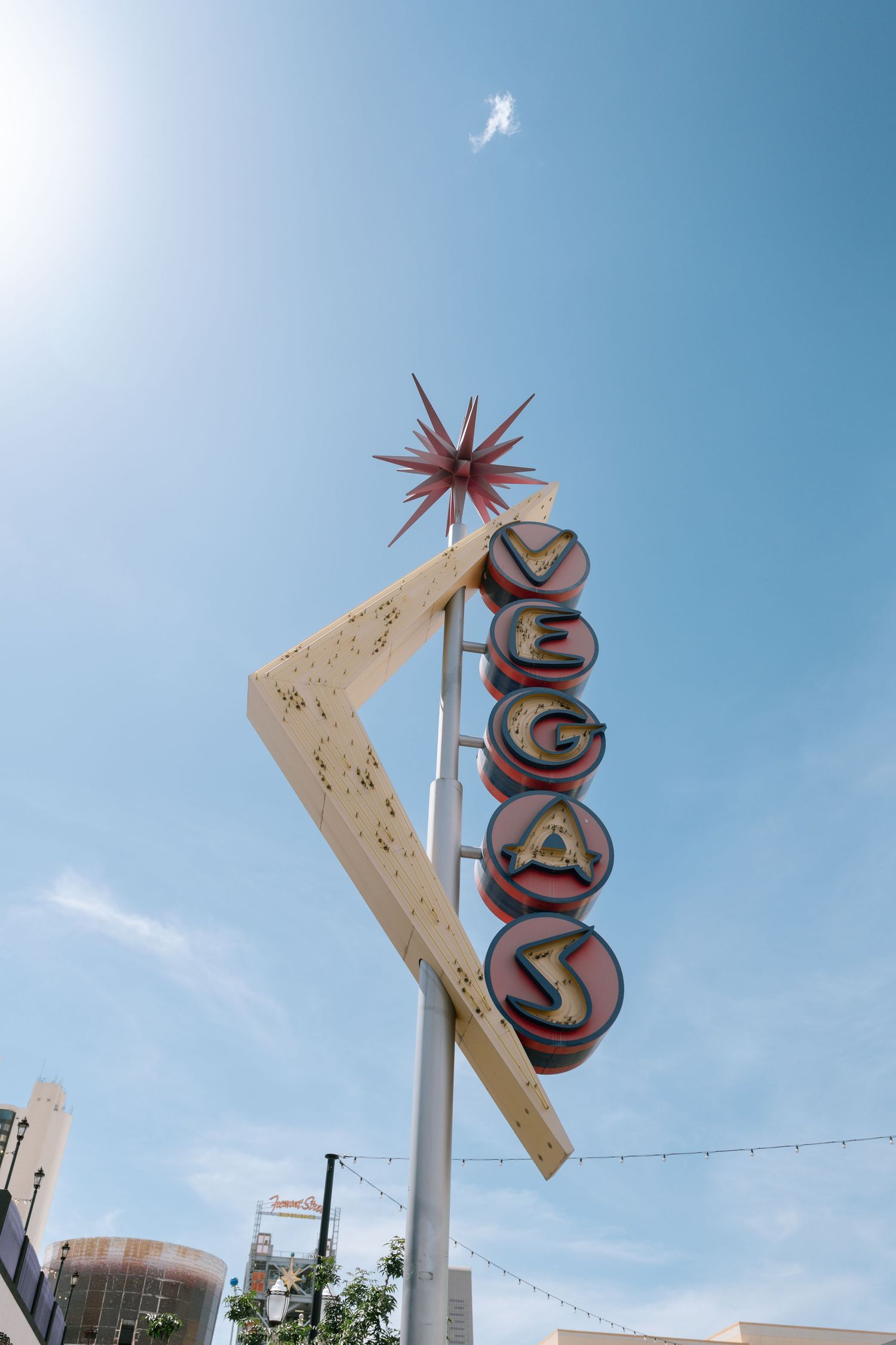 Vintage Vegas sign with starburst design against bright blue sky.