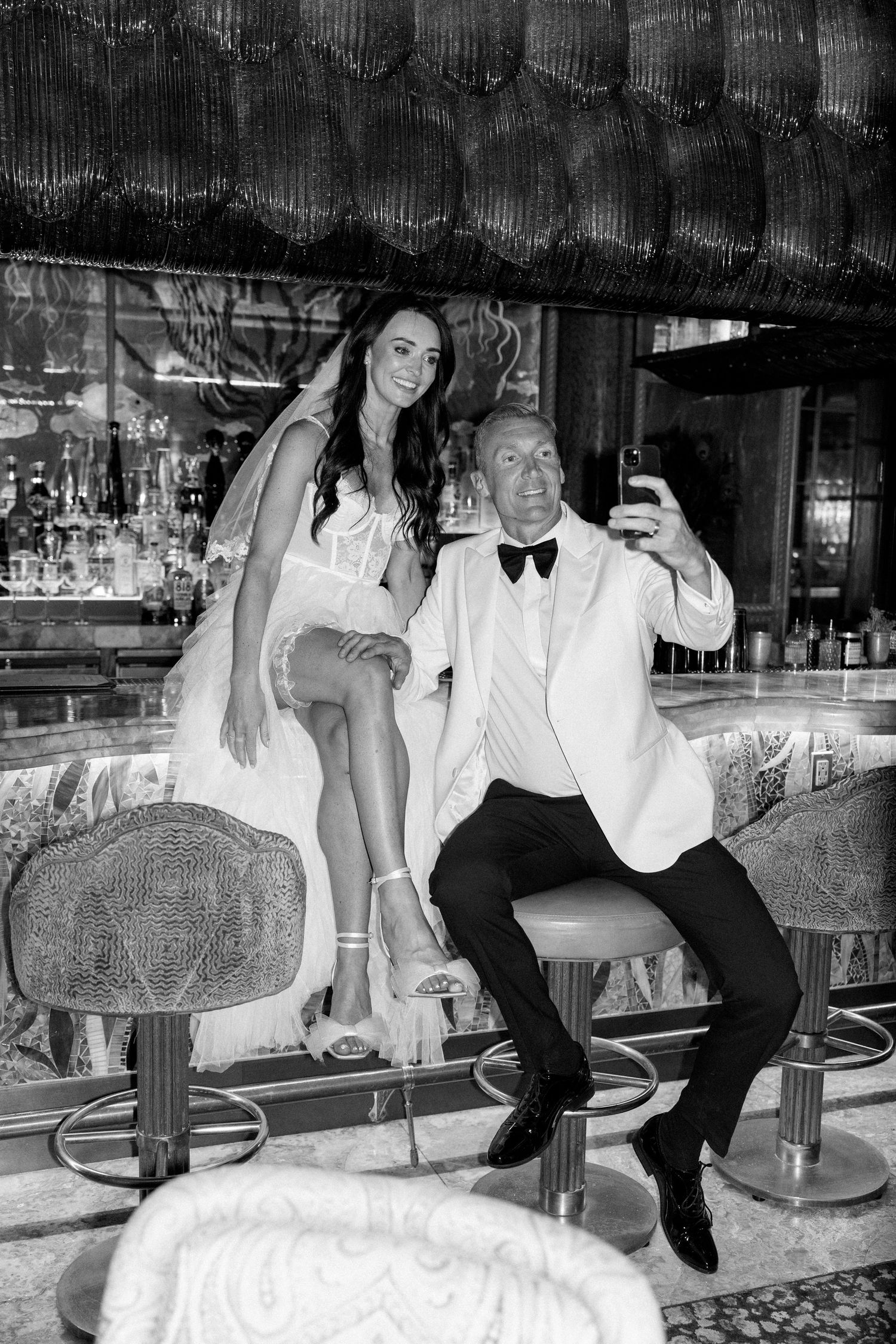 Newlyweds share intimate moments while seated at a vintage casino bar.