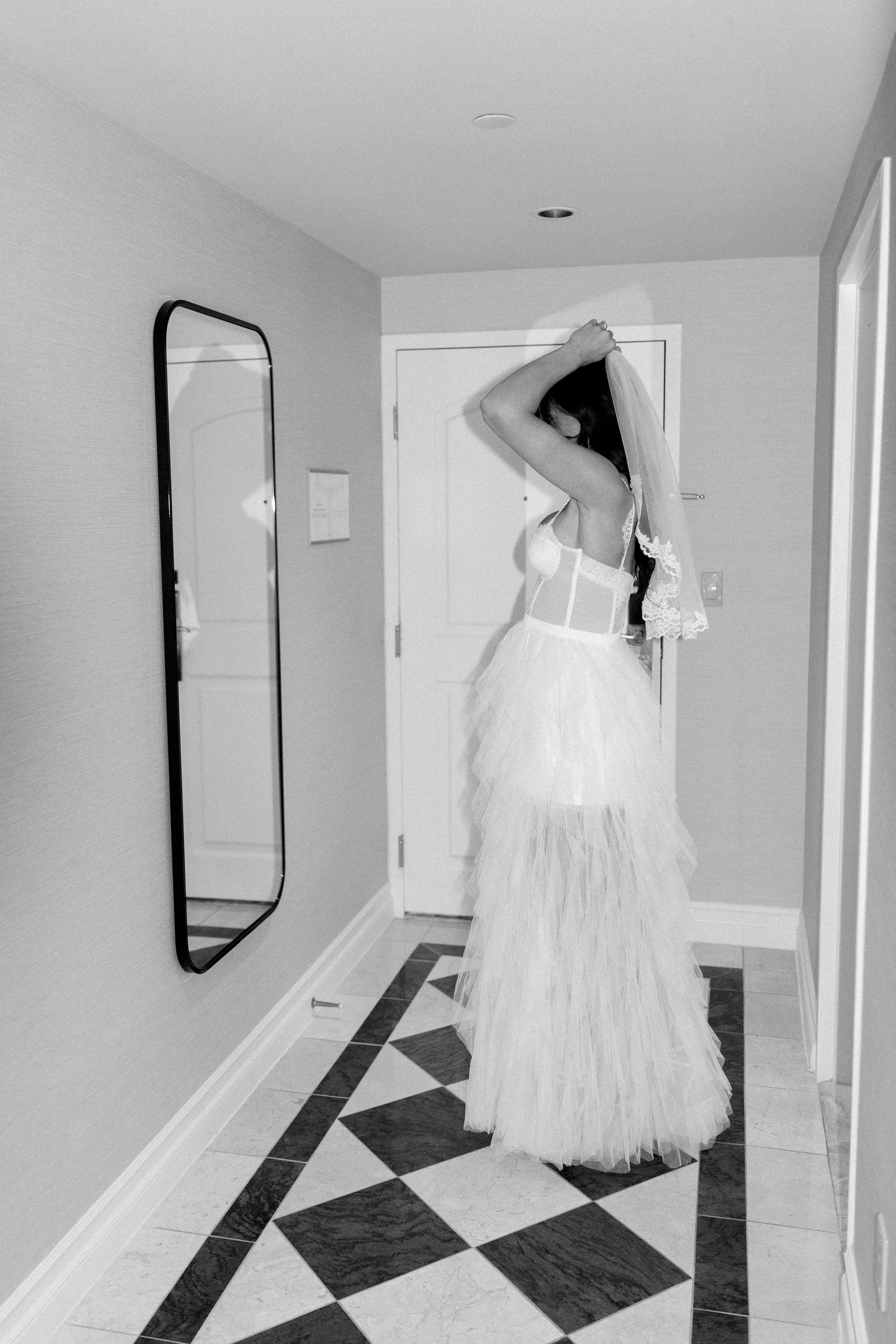 Artistic shot of bride in flowing dress posing in hallway with geometric floor.