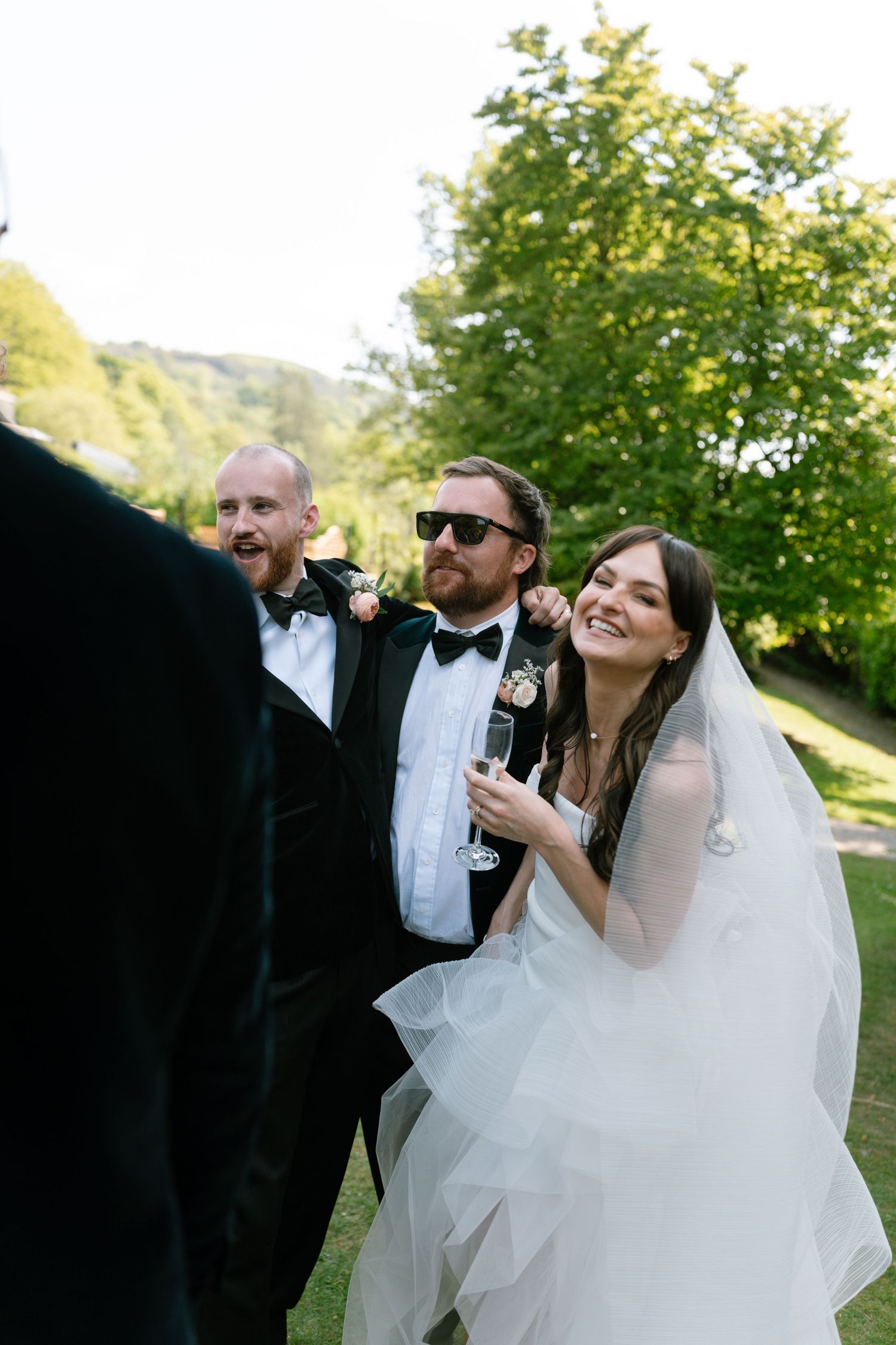 Joyful wedding celebration with guests in formal attire outdoors.
