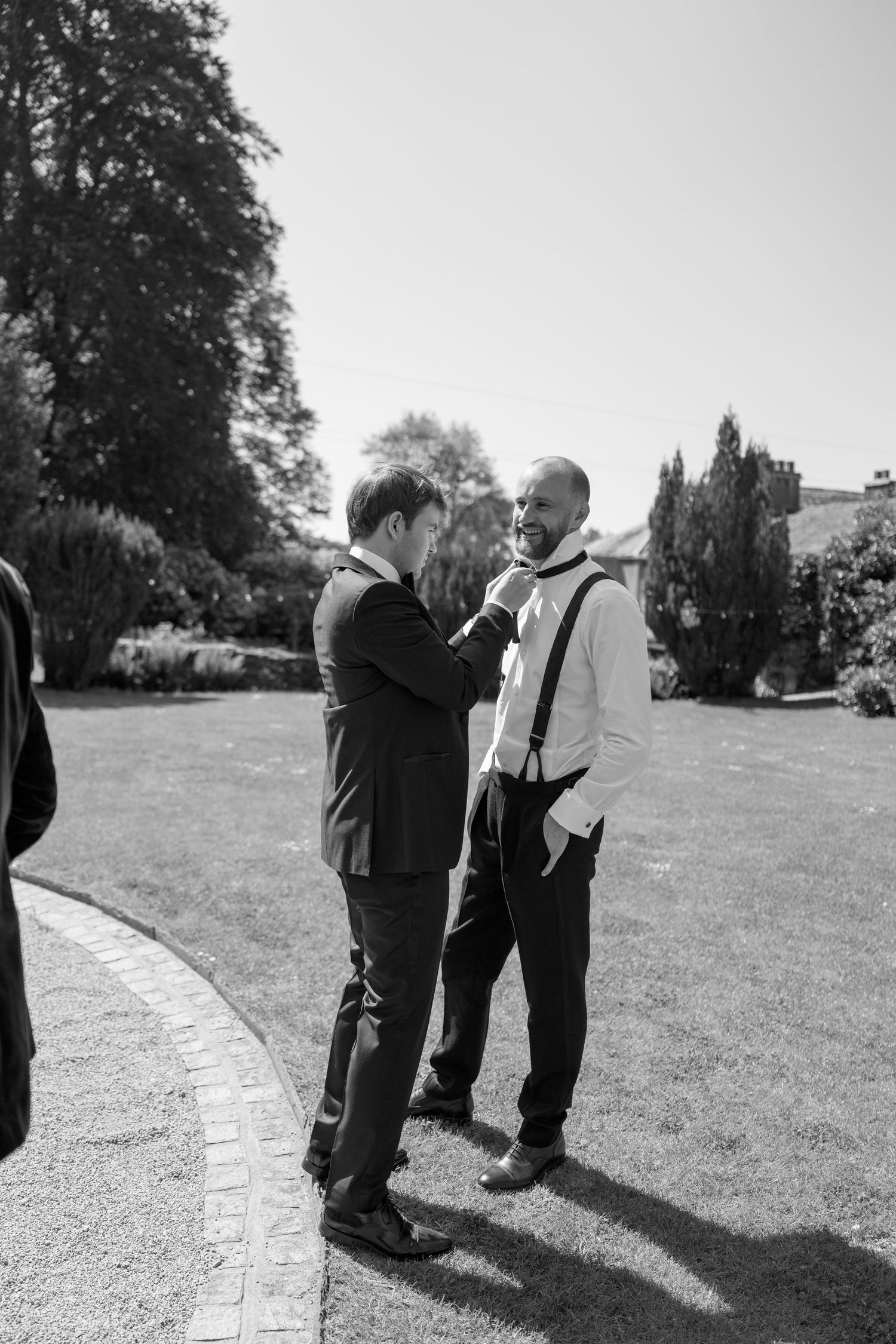 Black and white shot of people in formal wear standing on a curved pathway.