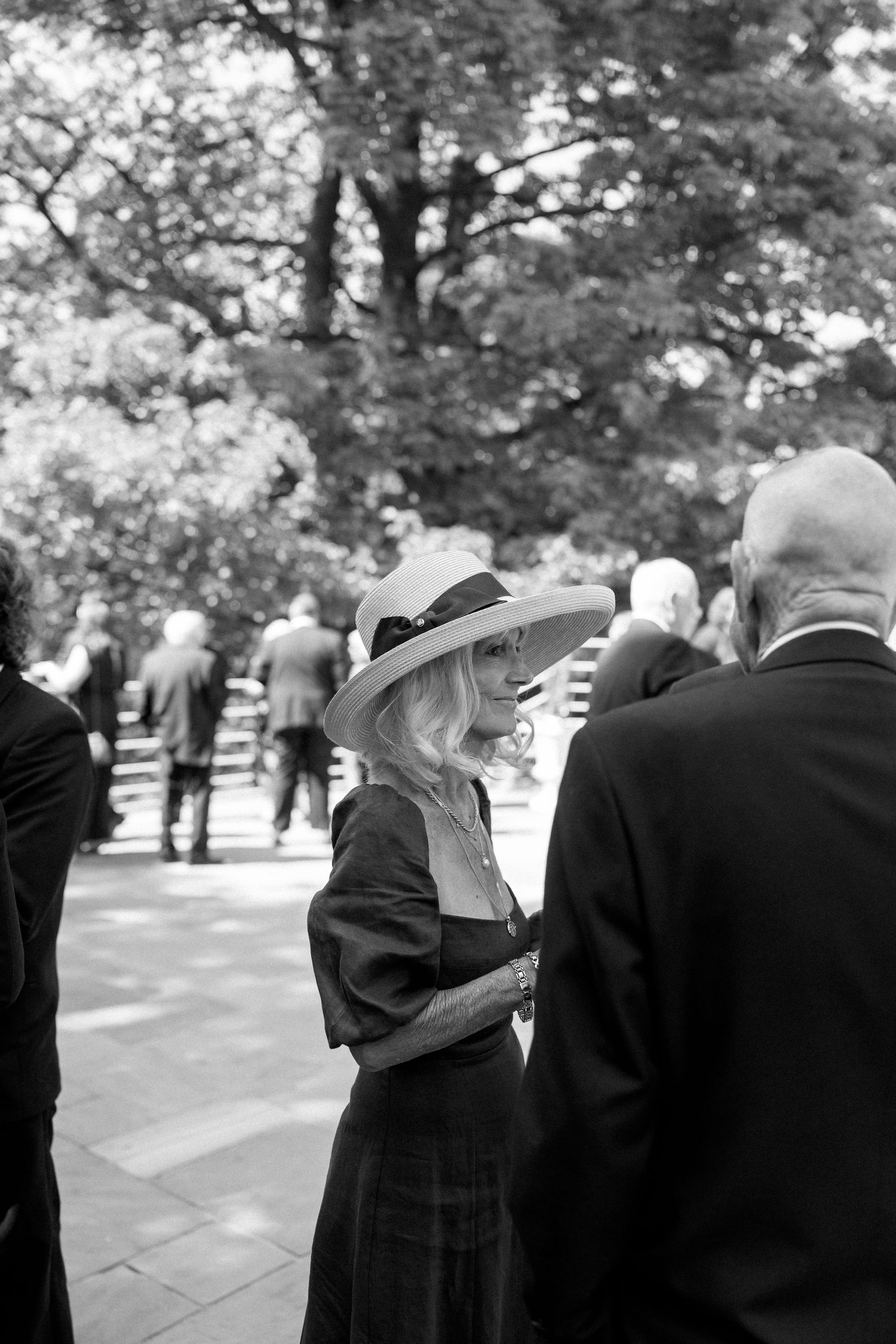 Black and white photo of guests mingling at a formal outdoor gathering.