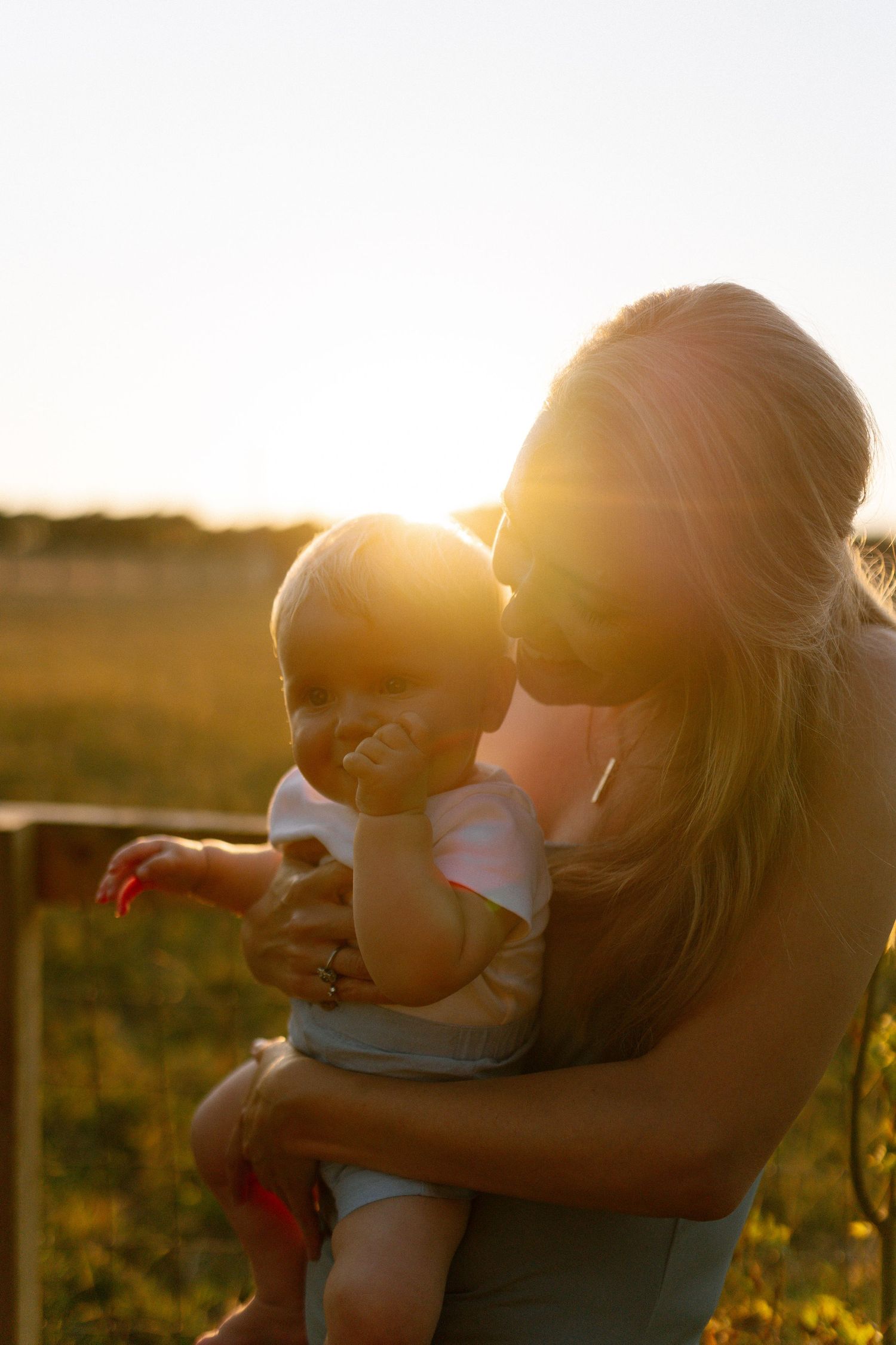 Intimate moments shared between figures backlit by warm golden sunset light in a field.
