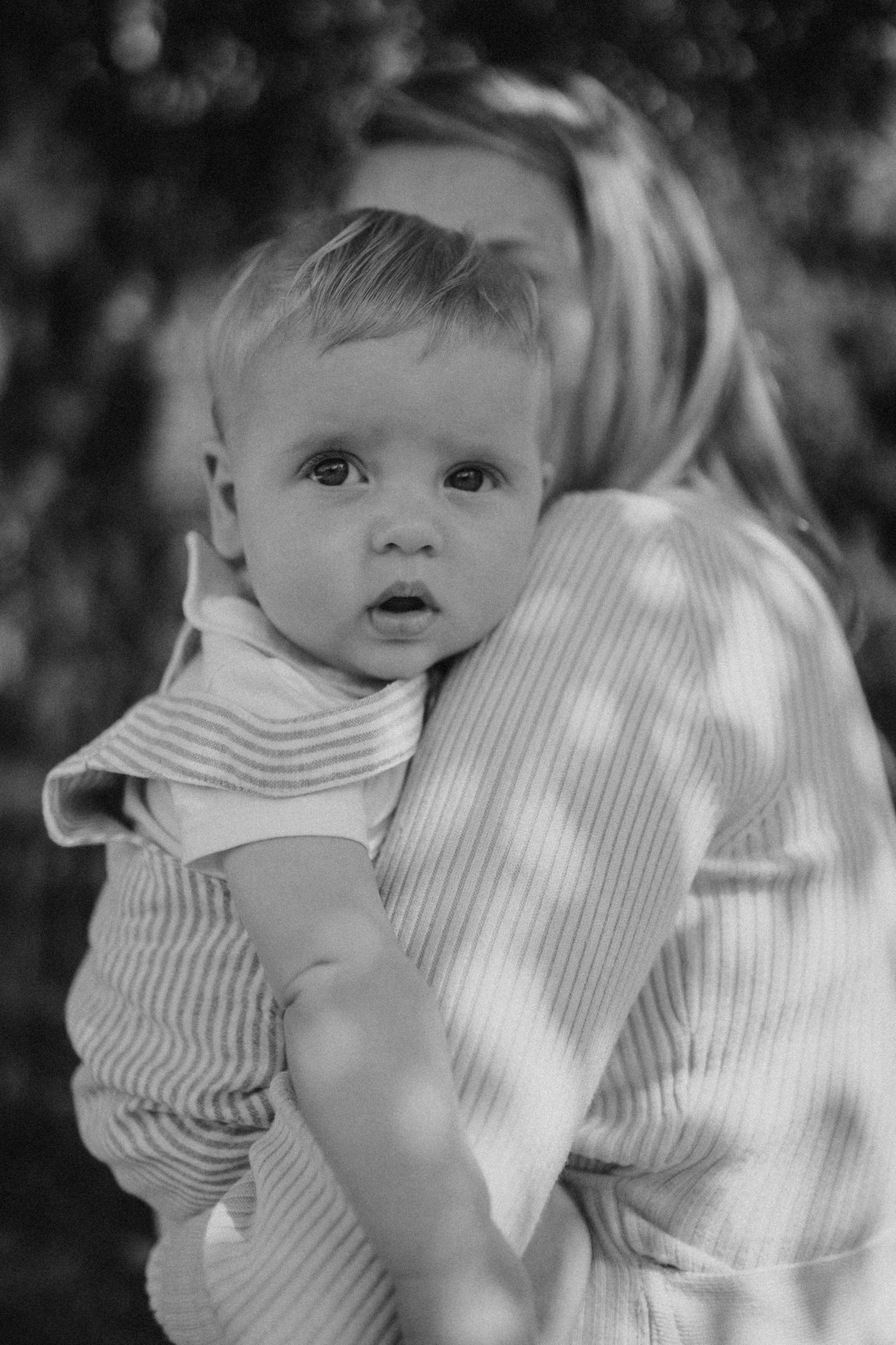 Close-up portrait in dappled sunlight showing tender family moment.