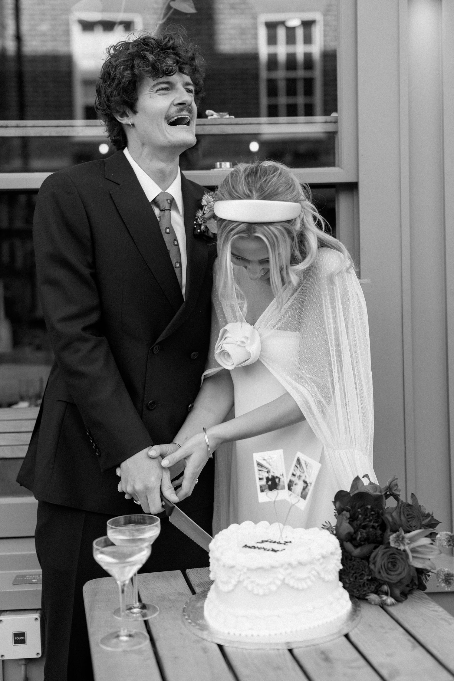 A candid moment of laughter while the newlyweds prepare to cut their wedding cake.