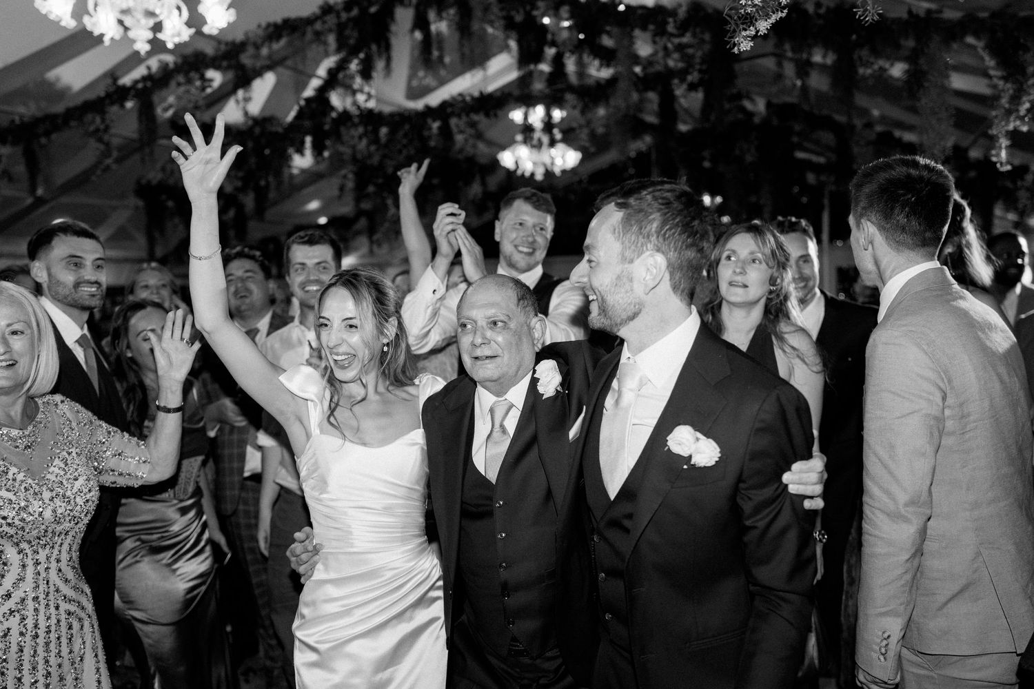 Wedding reception dance floor filled with joyful guests celebrating and dancing together.