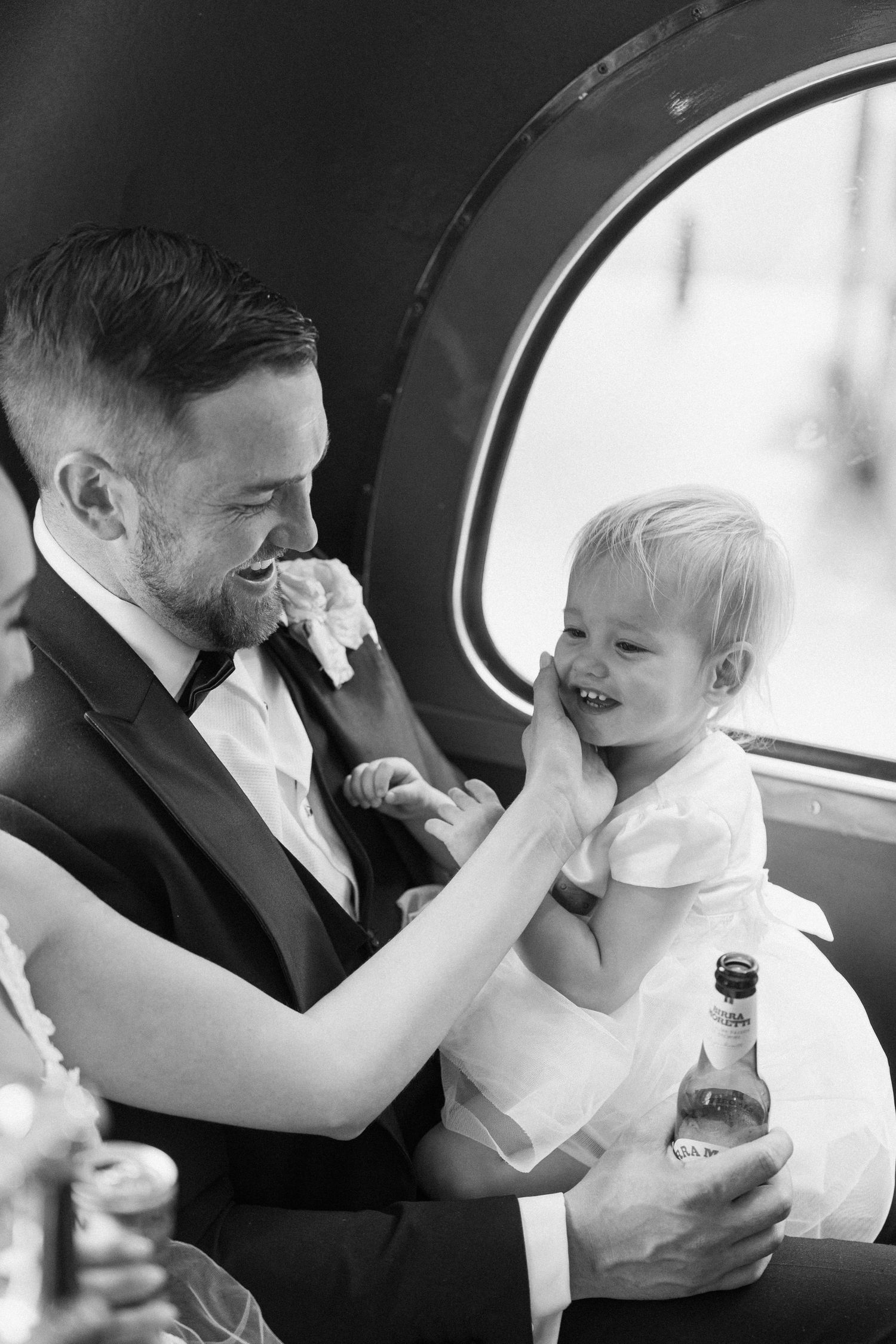 Joyful candid moments captured inside vintage London bus during wedding celebration.