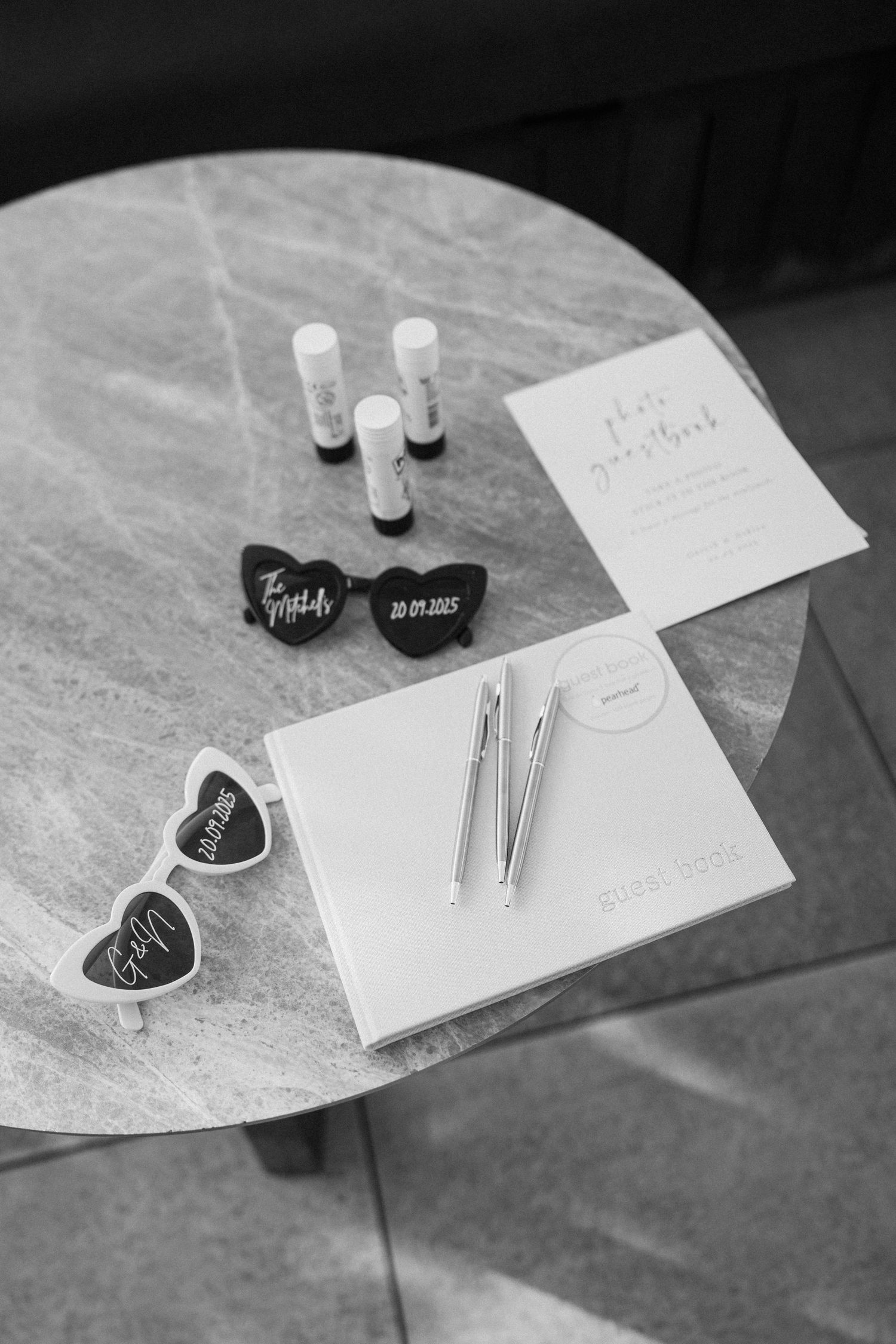 Wedding stationery and small decorative items arranged on a marble surface.