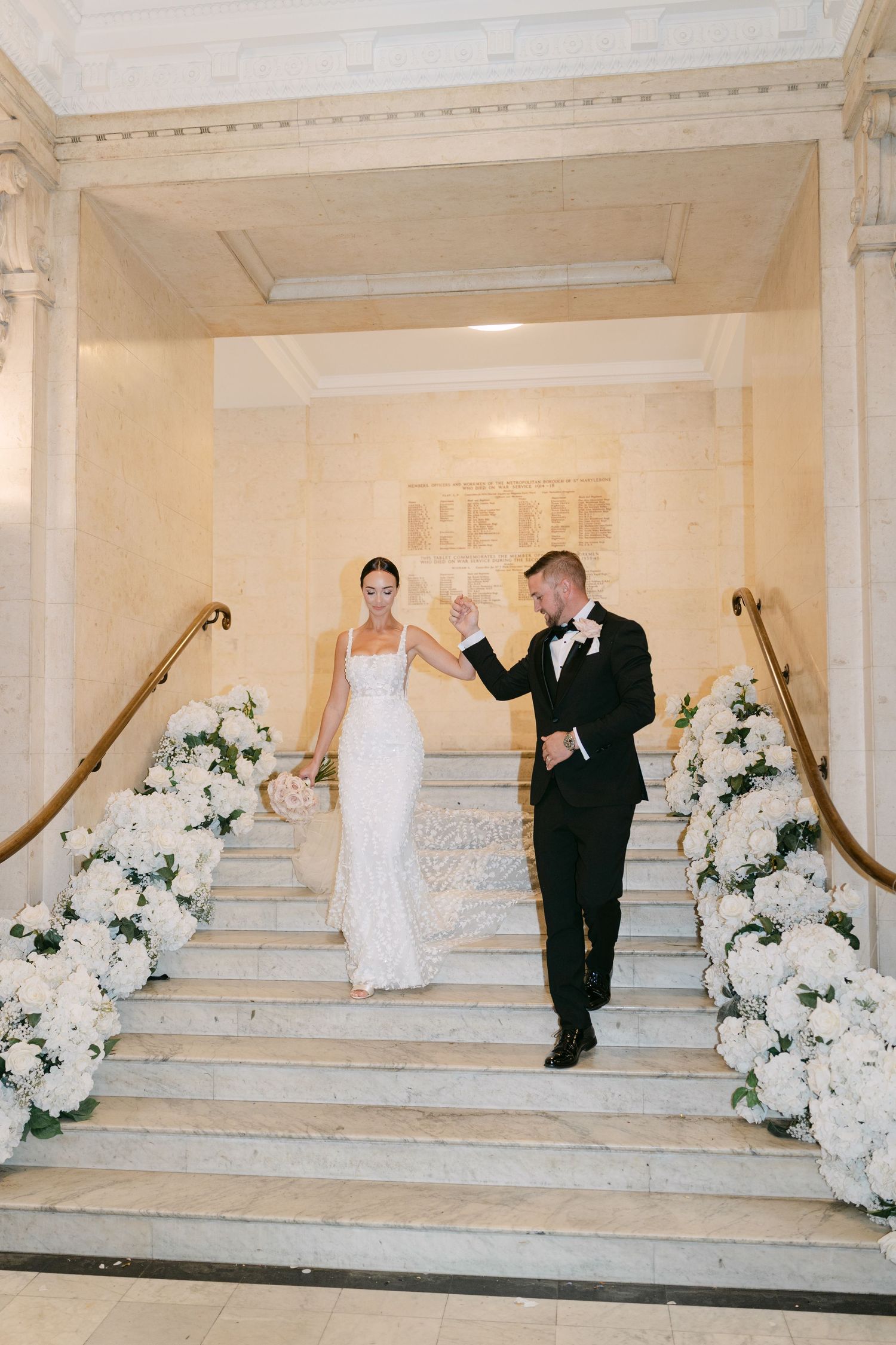 Elegant staircase adorned with white flower arrangements for wedding ceremony.