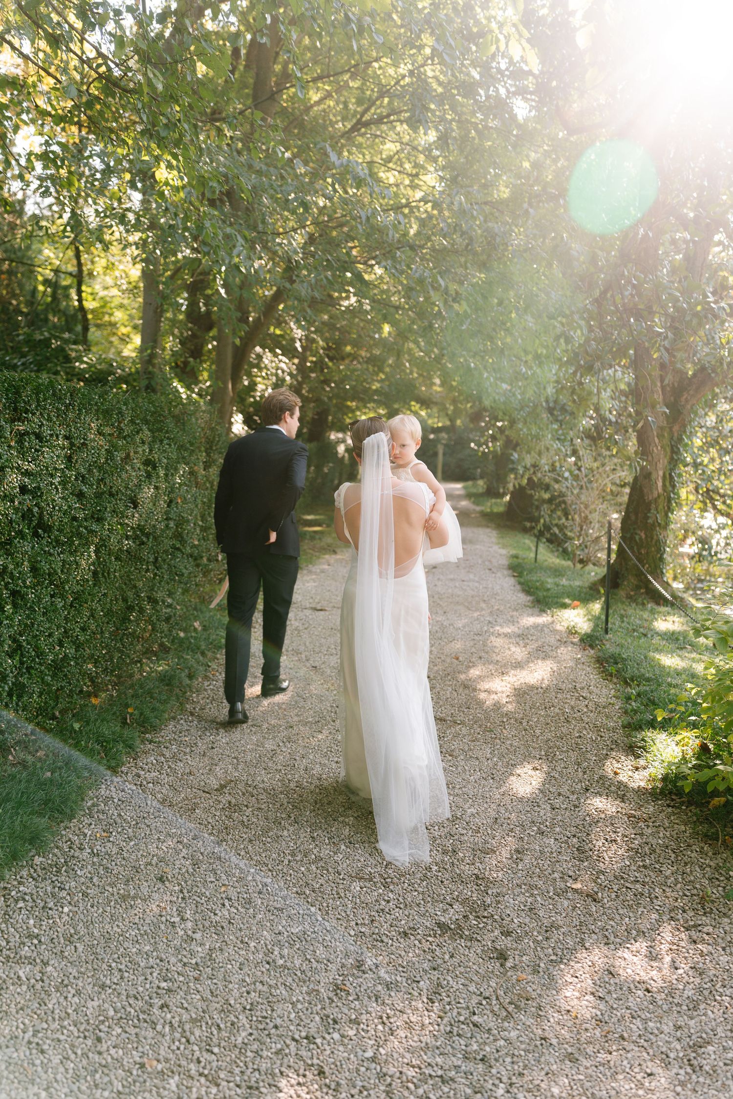 Couple walking along a sunlit garden path during golden hour.