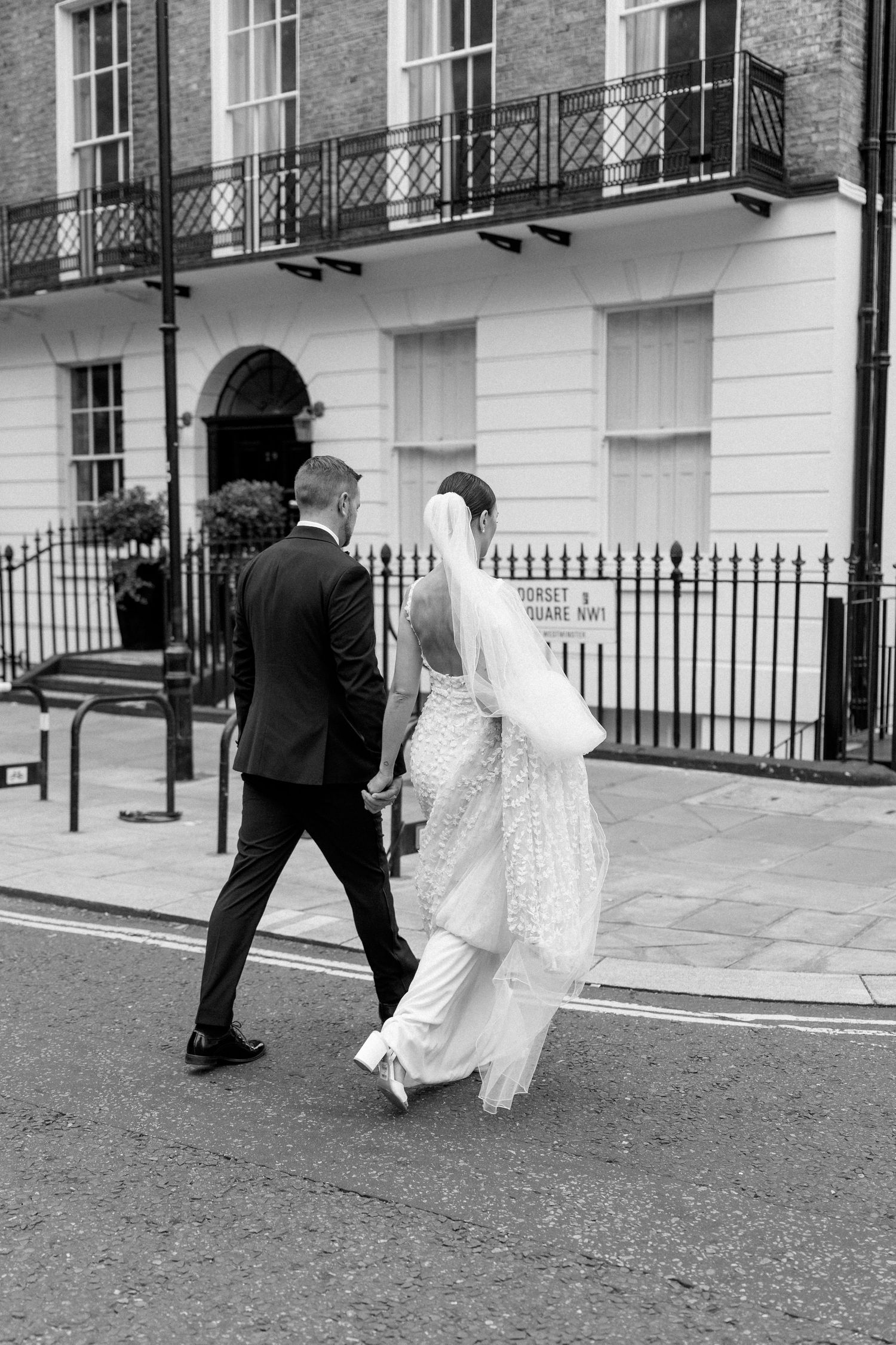 Wedding couple walking along historic London street with classic architecture.