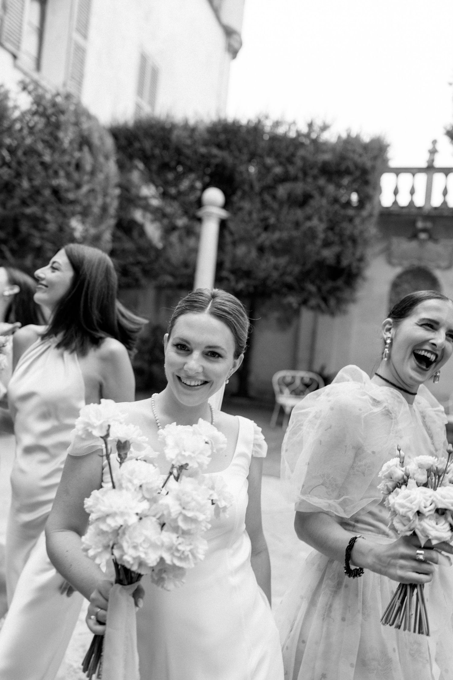 Candid black and white photo showing joyful laughter during wedding party portraits.