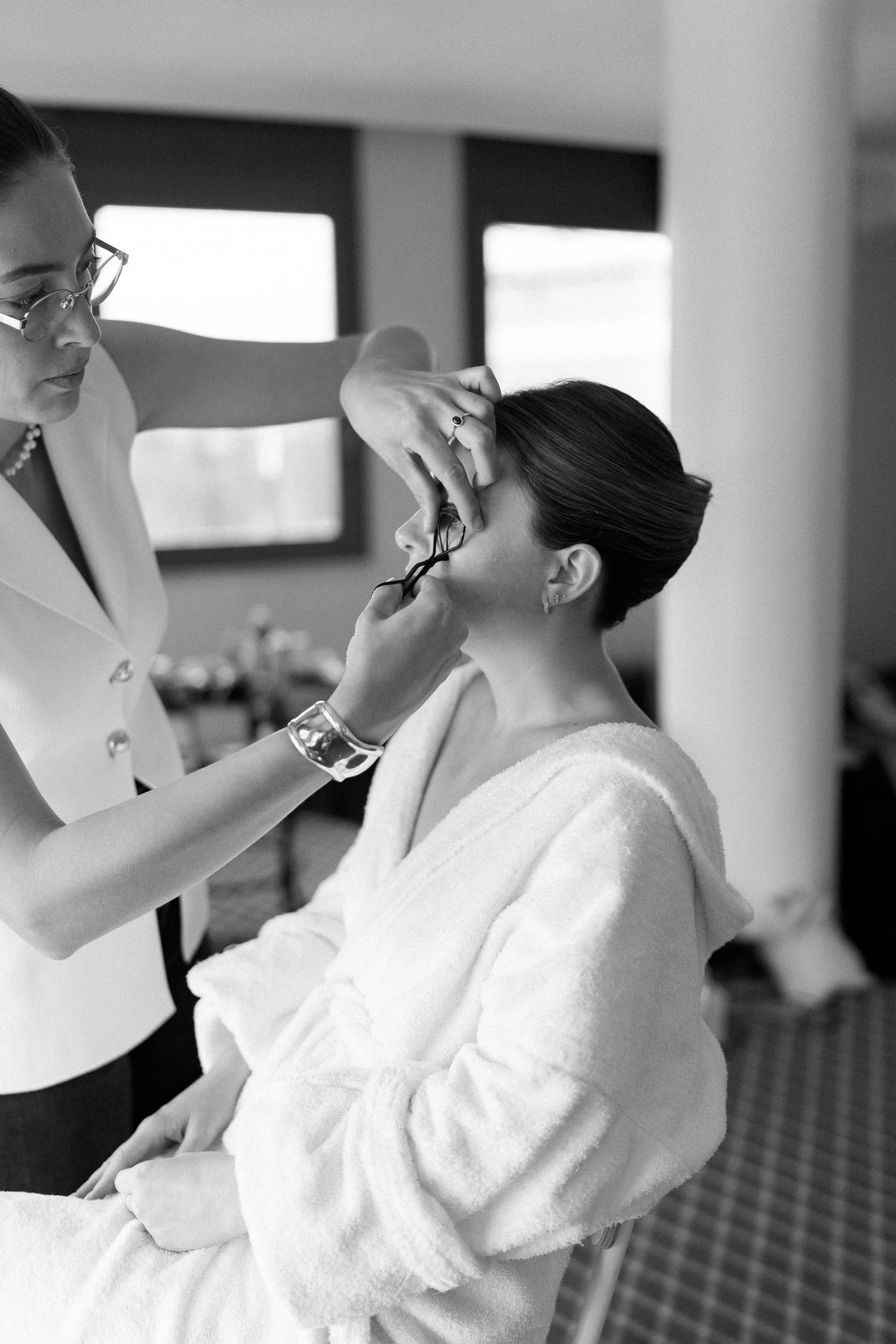 Person in white robe getting makeup applied in preparation for event.
