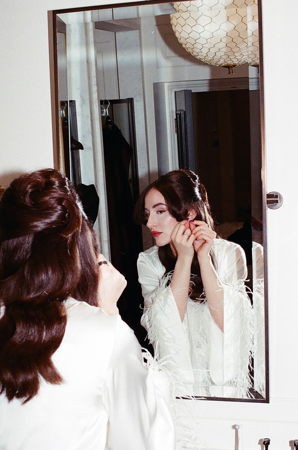 A series of mirror reflections show someone in a white robe applying eye makeup in a bathroom setting.