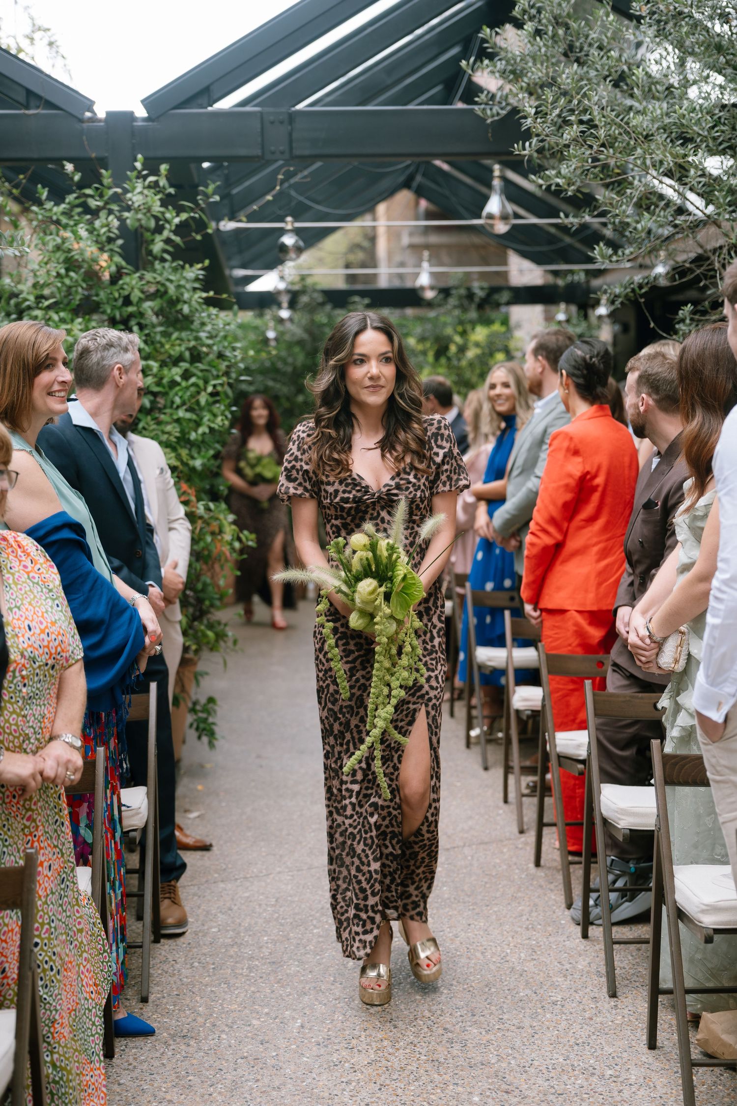Wedding guests mingle and chat during an outdoor reception under a covered pavilion.