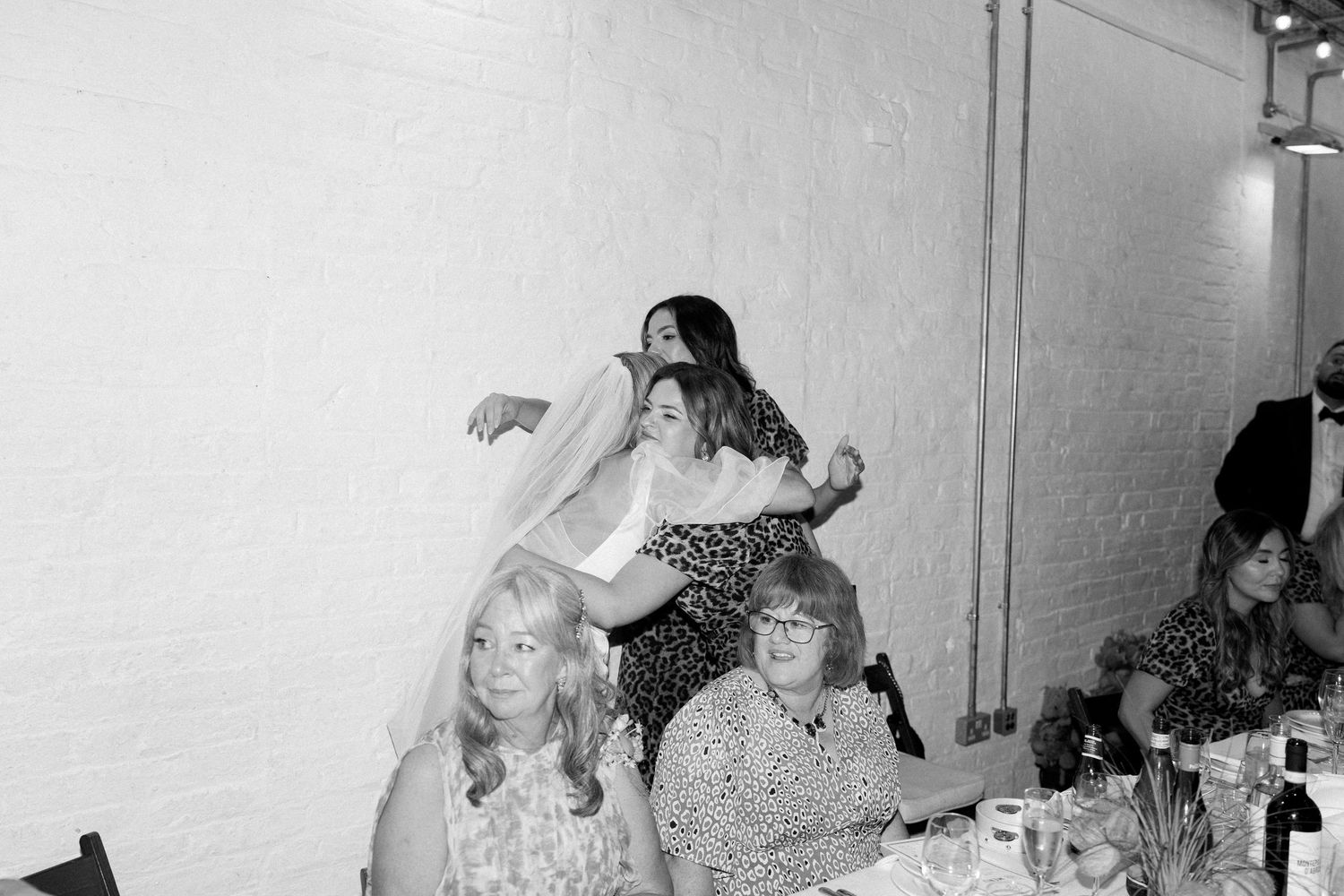 Wedding guests share a candid moment of laughter at a reception.