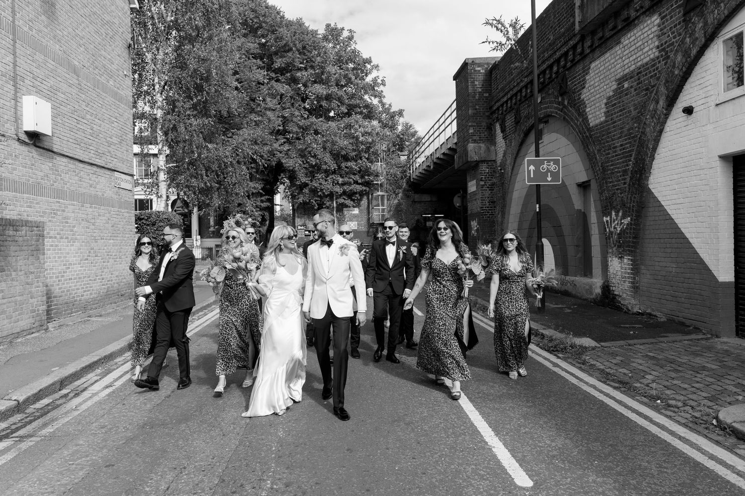 Wedding party walks together down a charming cobblestone street.