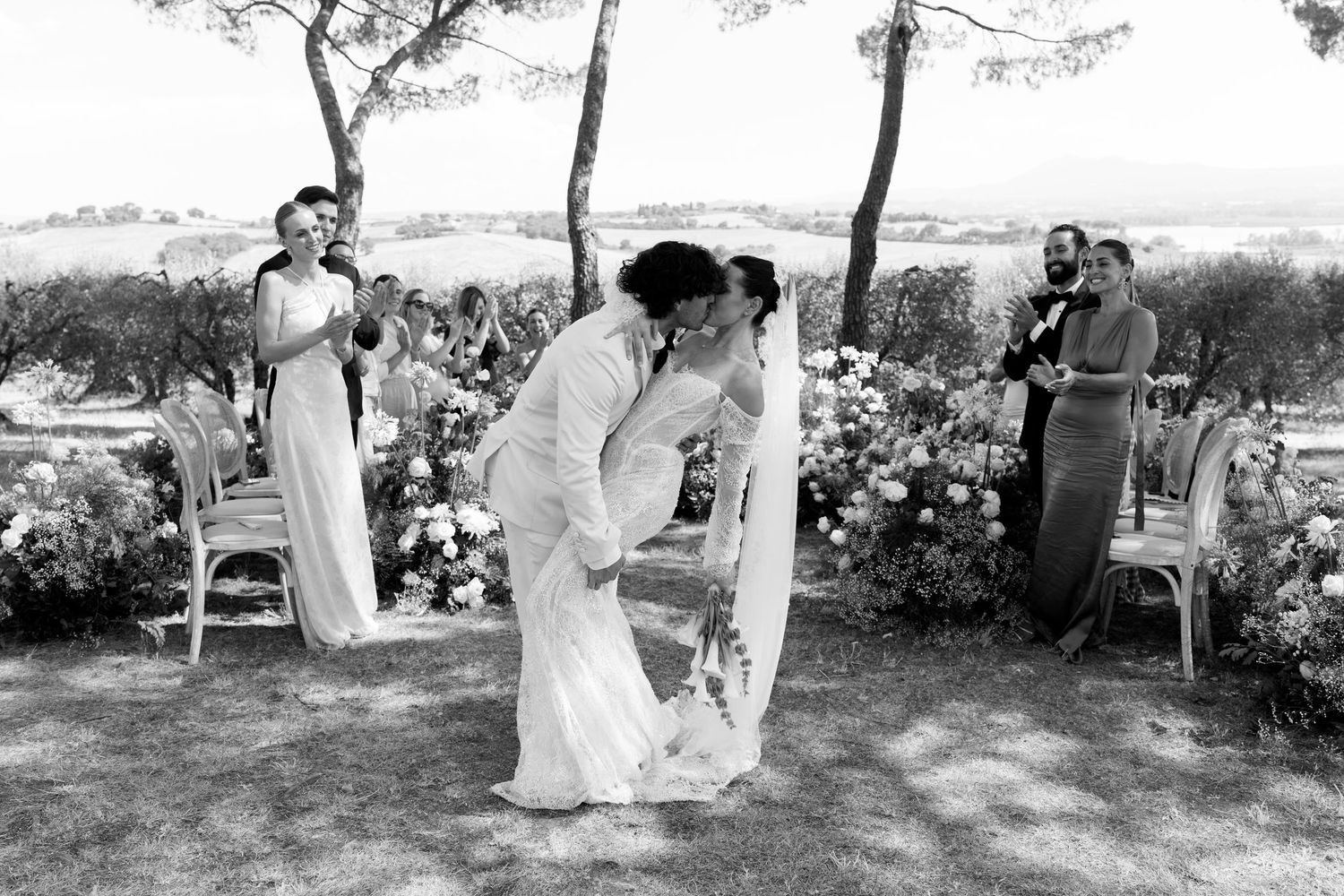 Black and white photograph of a wedding ceremony moment in a garden setting.