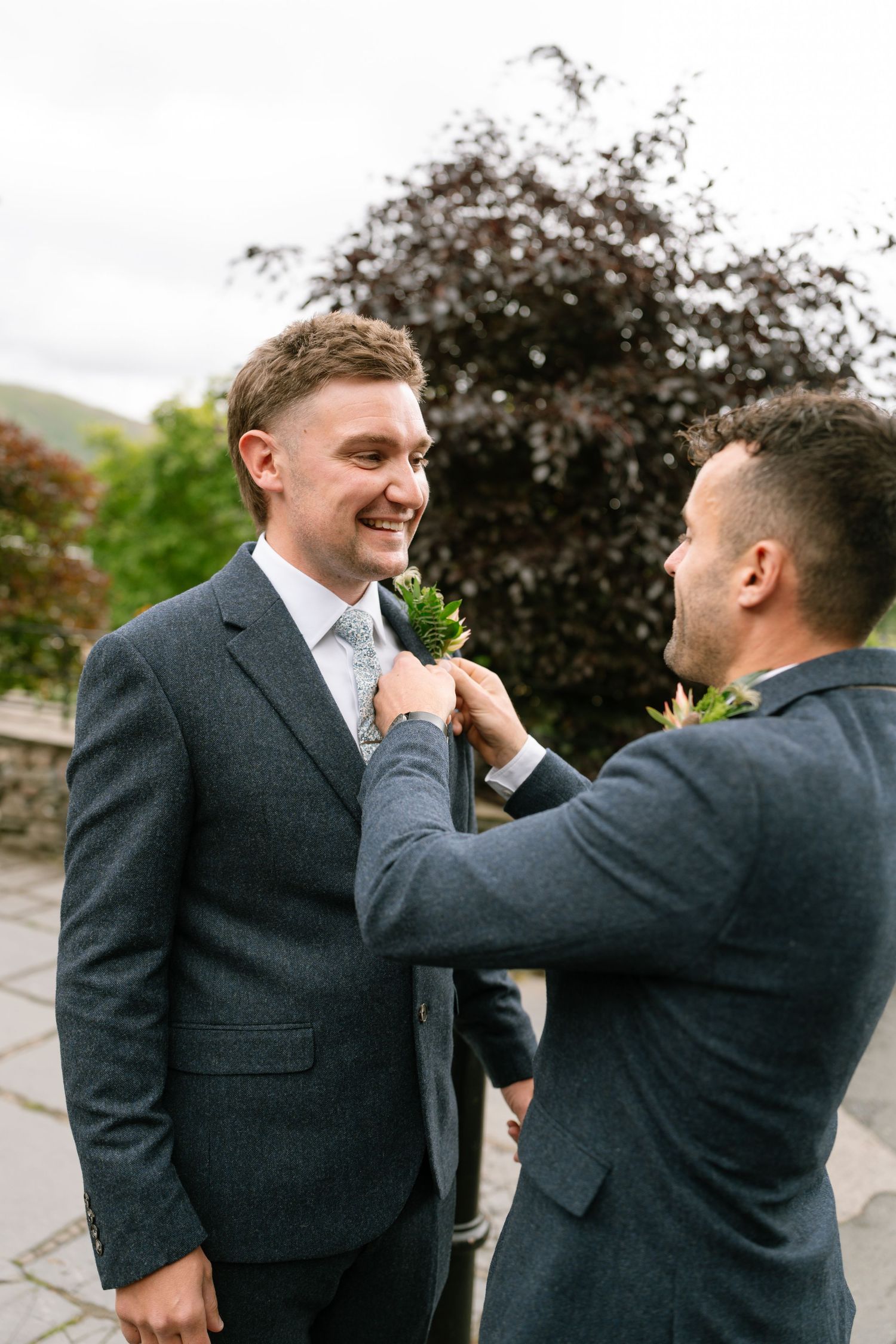 Groomsmen sharing a lighthearted moment while adjusting boutonnieres before the ceremony.