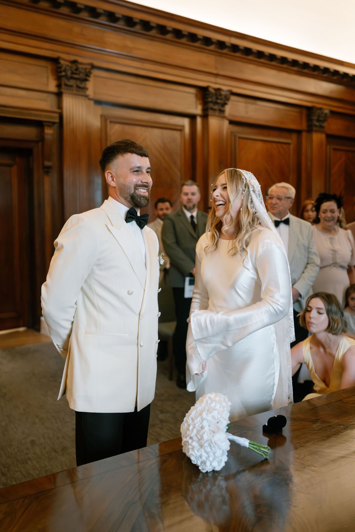 A couple shares their first dance in a grand wood-paneled ballroom during their wedding reception.