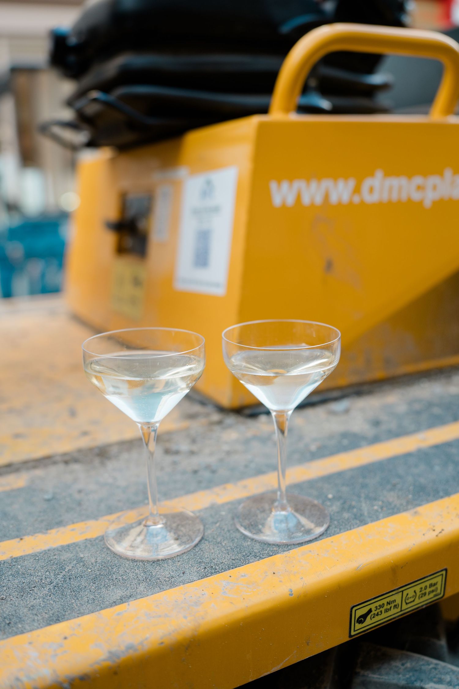 Two martini glasses placed on yellow construction equipment.