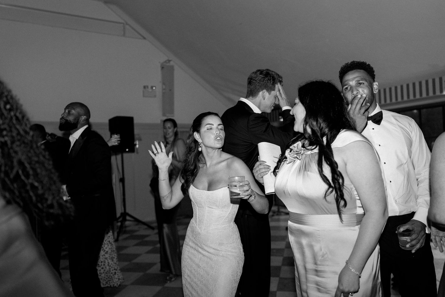 Wedding guests dance and celebrate joyfully on the dance floor in black and white photo.