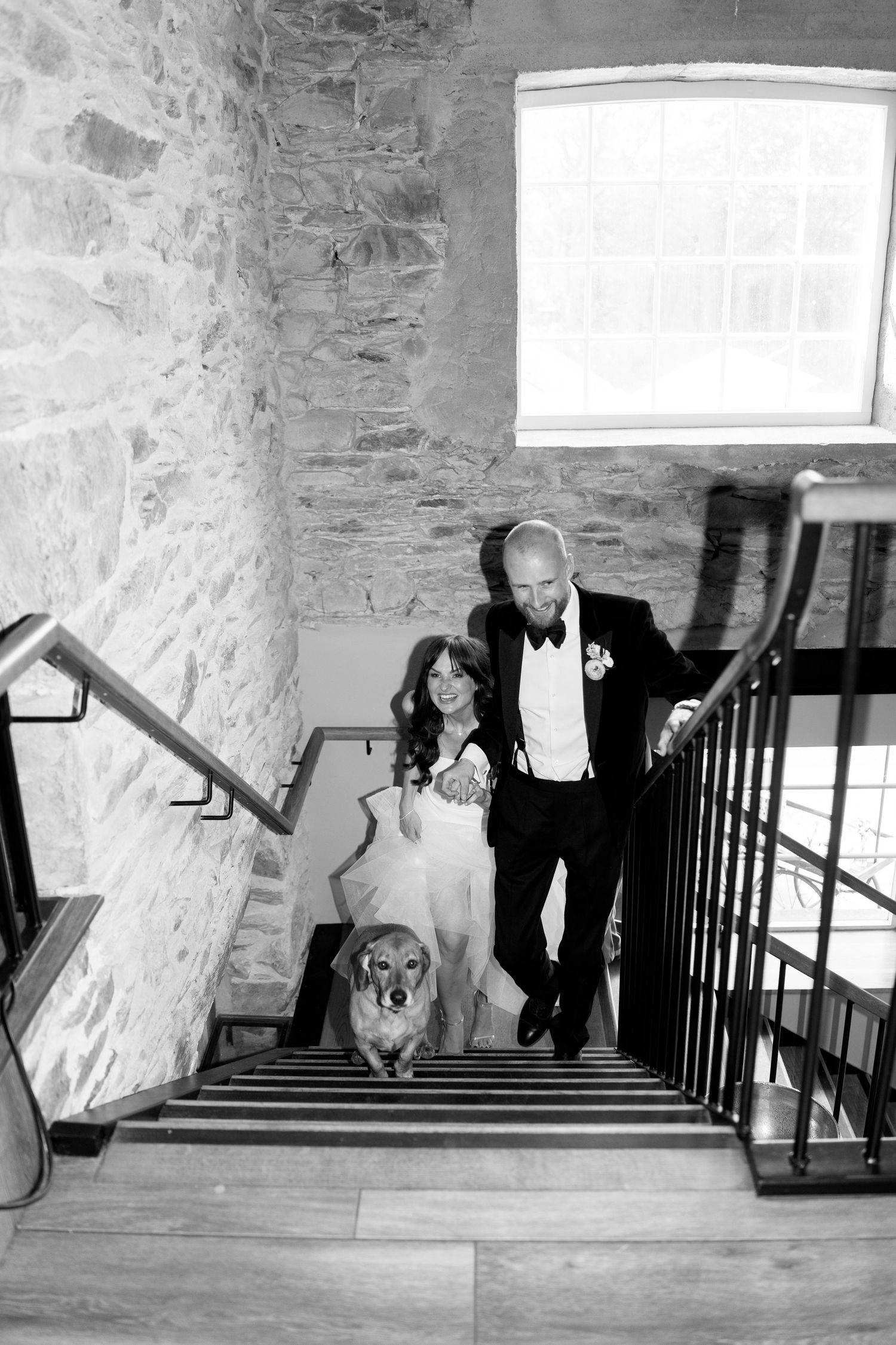 Wedding party descending stone staircase in rustic venue.
